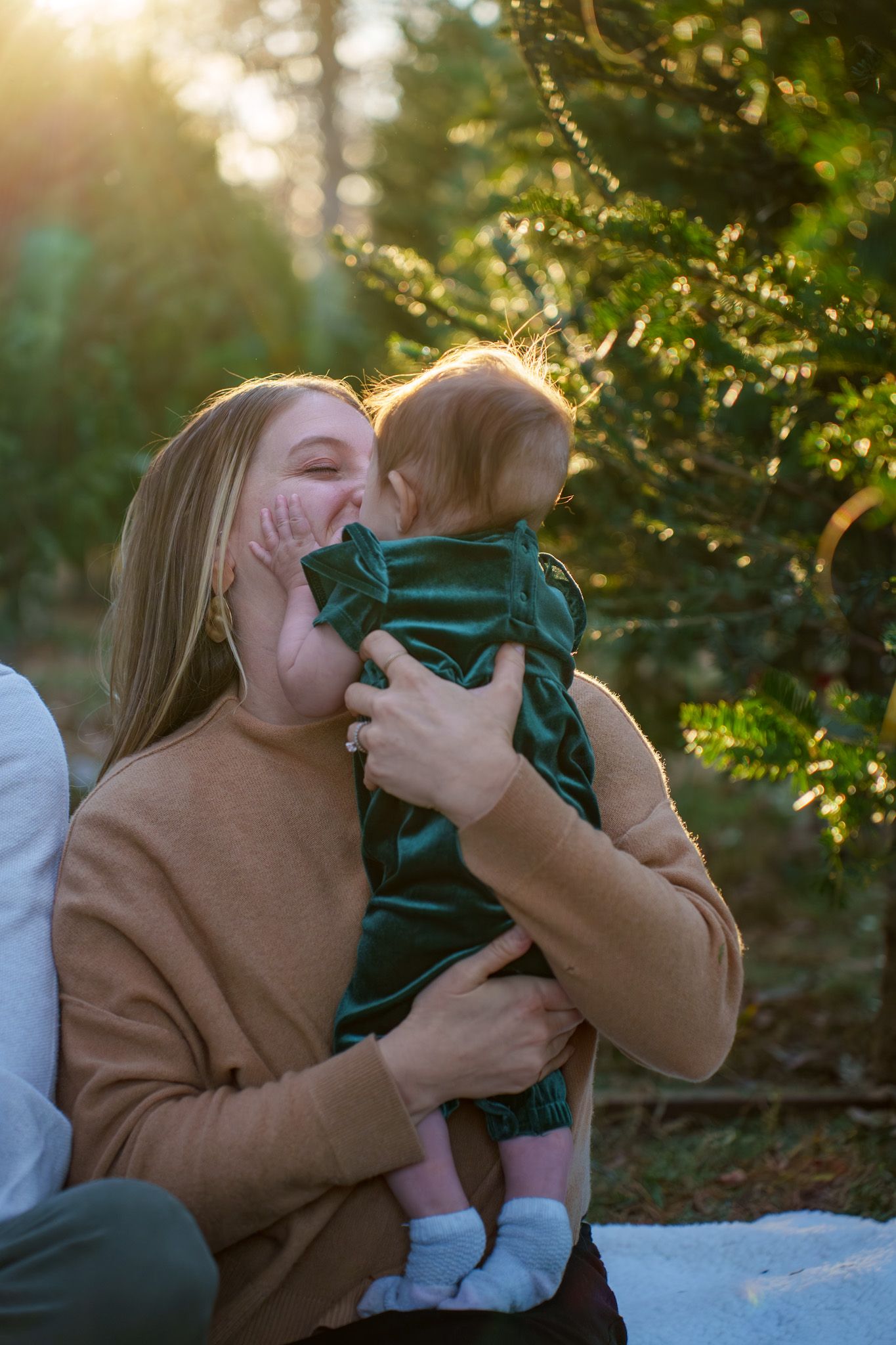 A joyful embrace shared between parent and child amid sunlit evergreen trees.