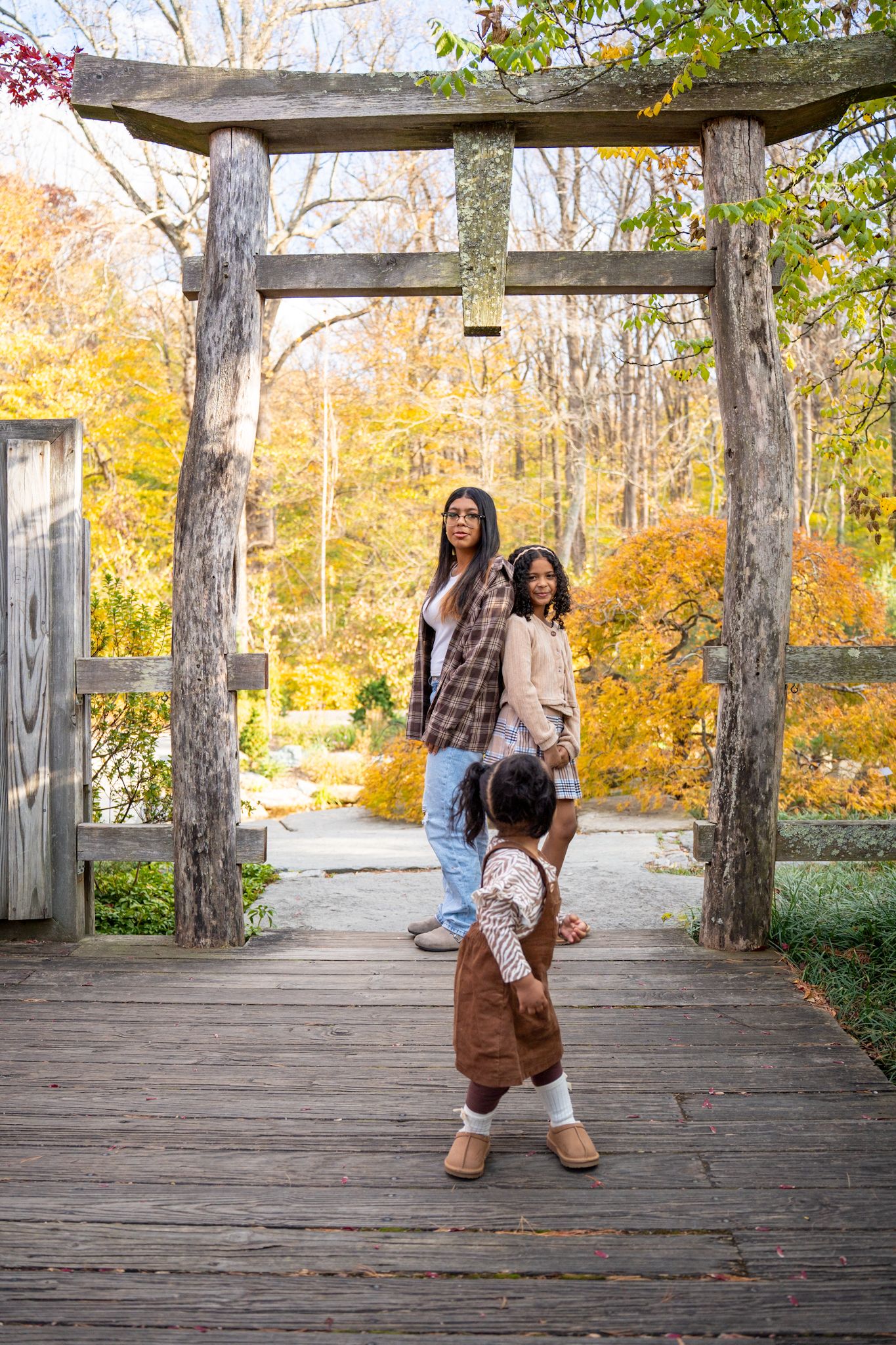 Autumn scene with wooden gazebo and fall foliage in background as figures enjoy a casual outdoor moment.