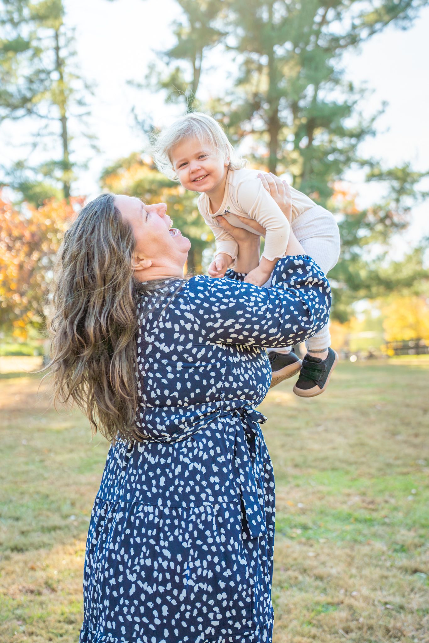 A joyful moment captured outdoors in a grassy field with pine trees during golden hour.