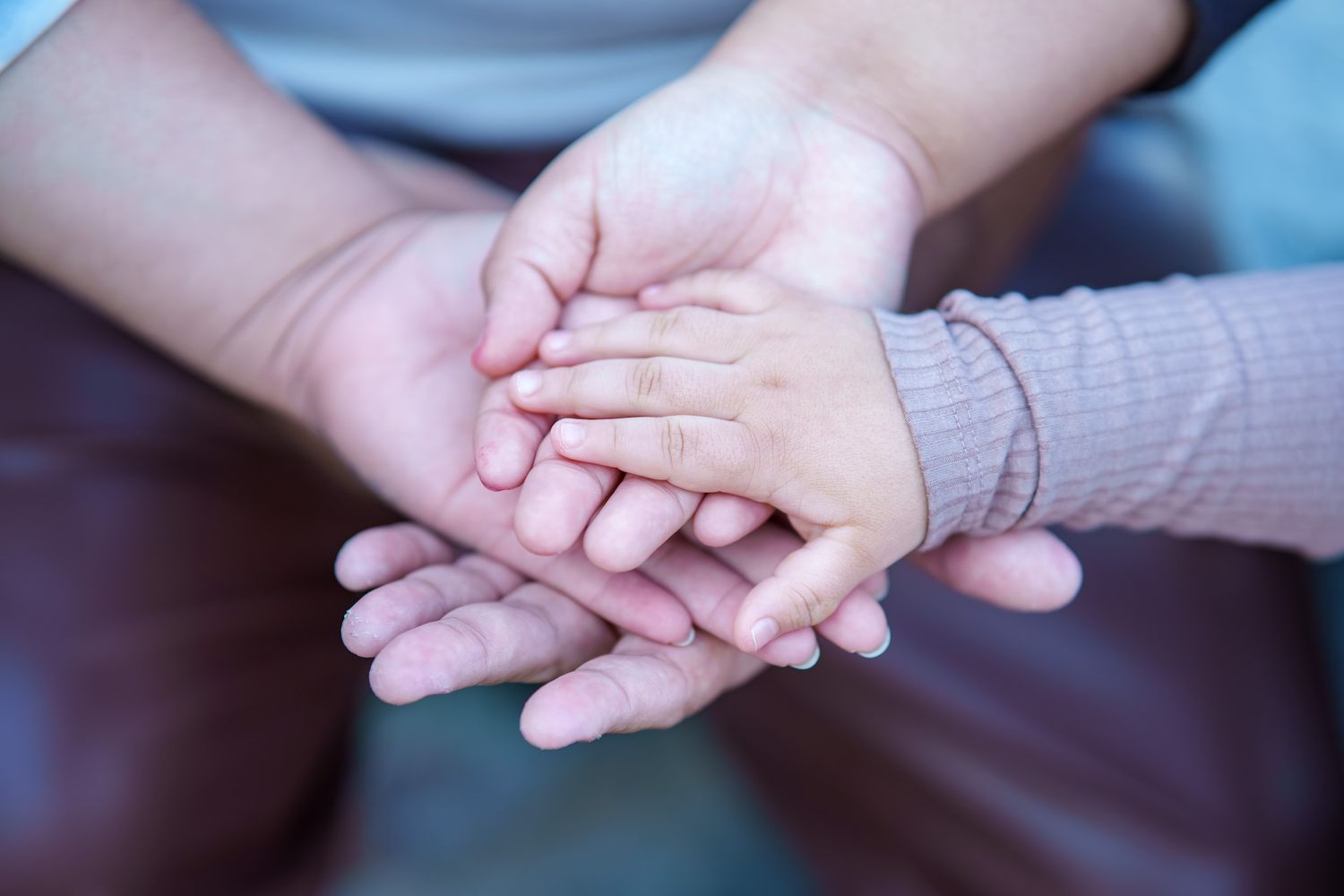 Hands gently clasped together in a supportive gesture showing care and connection between two people.