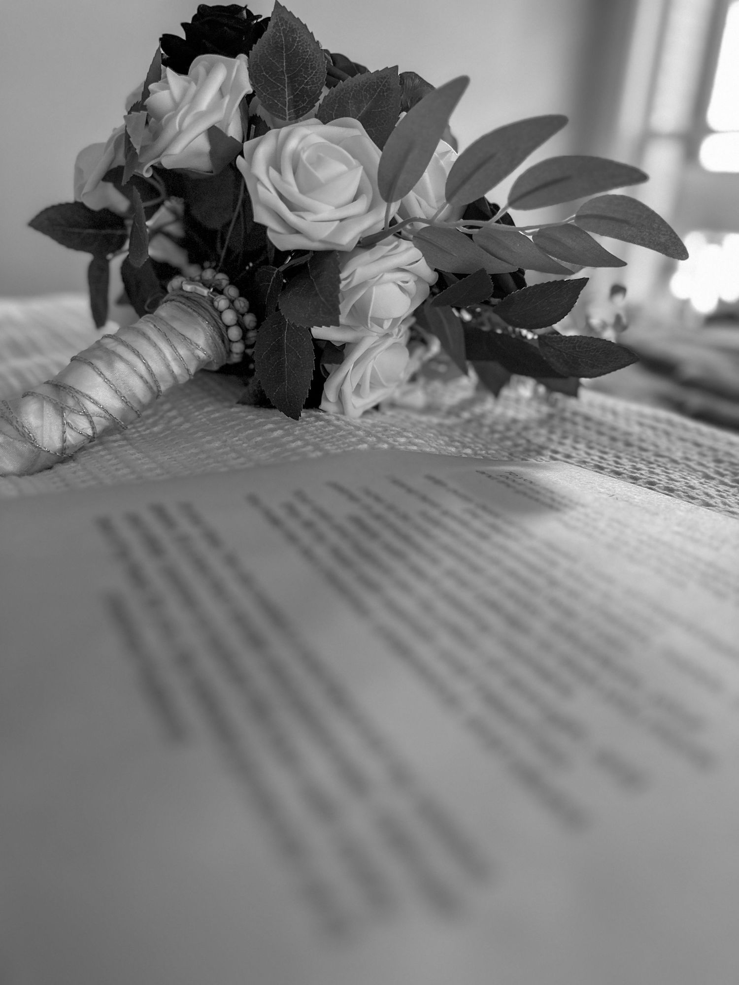 Close-up of wedding flowers and text on paper with soft window light.