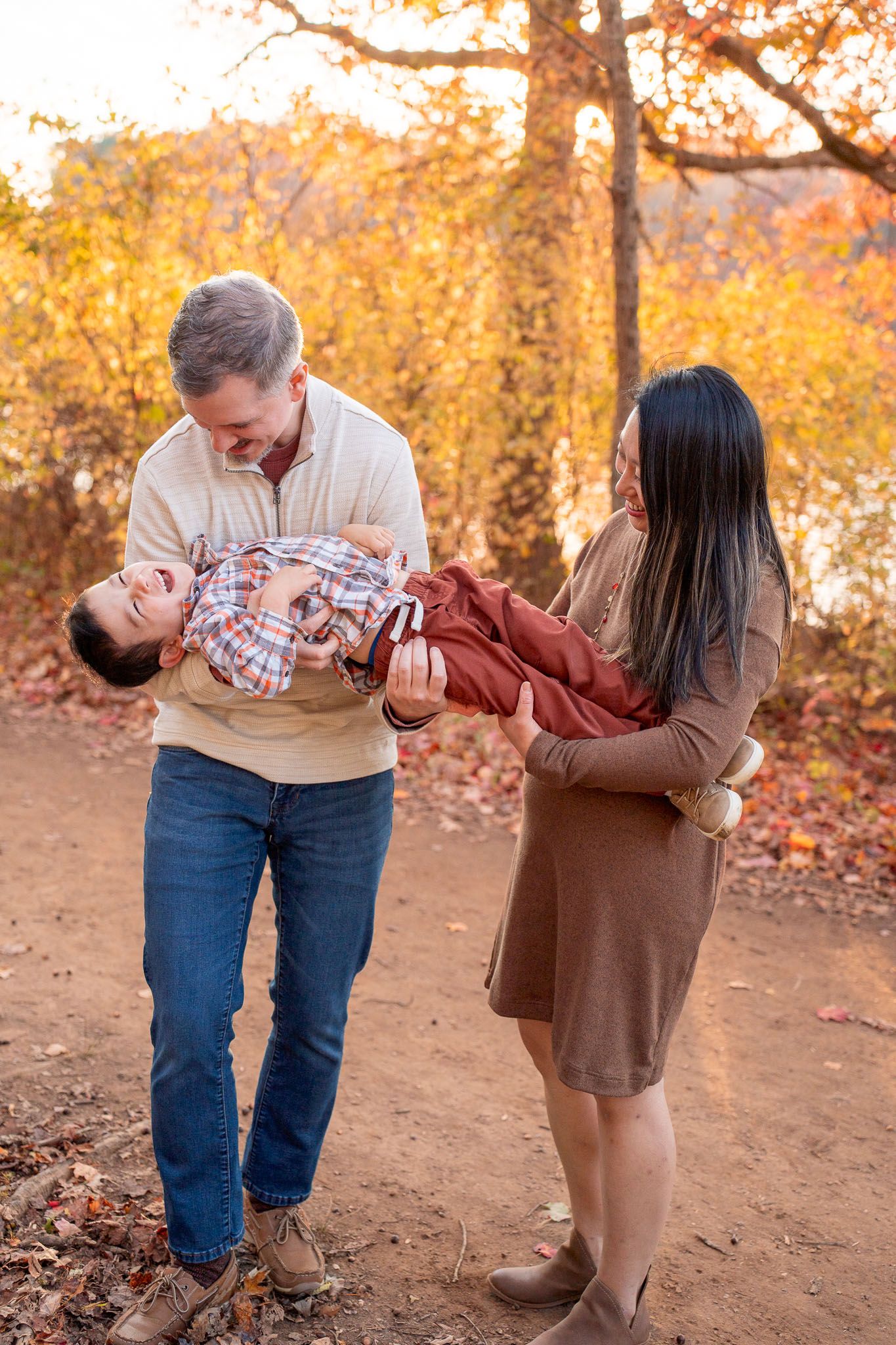 Family sharing joyful moments together on an autumn trail with fallen leaves.