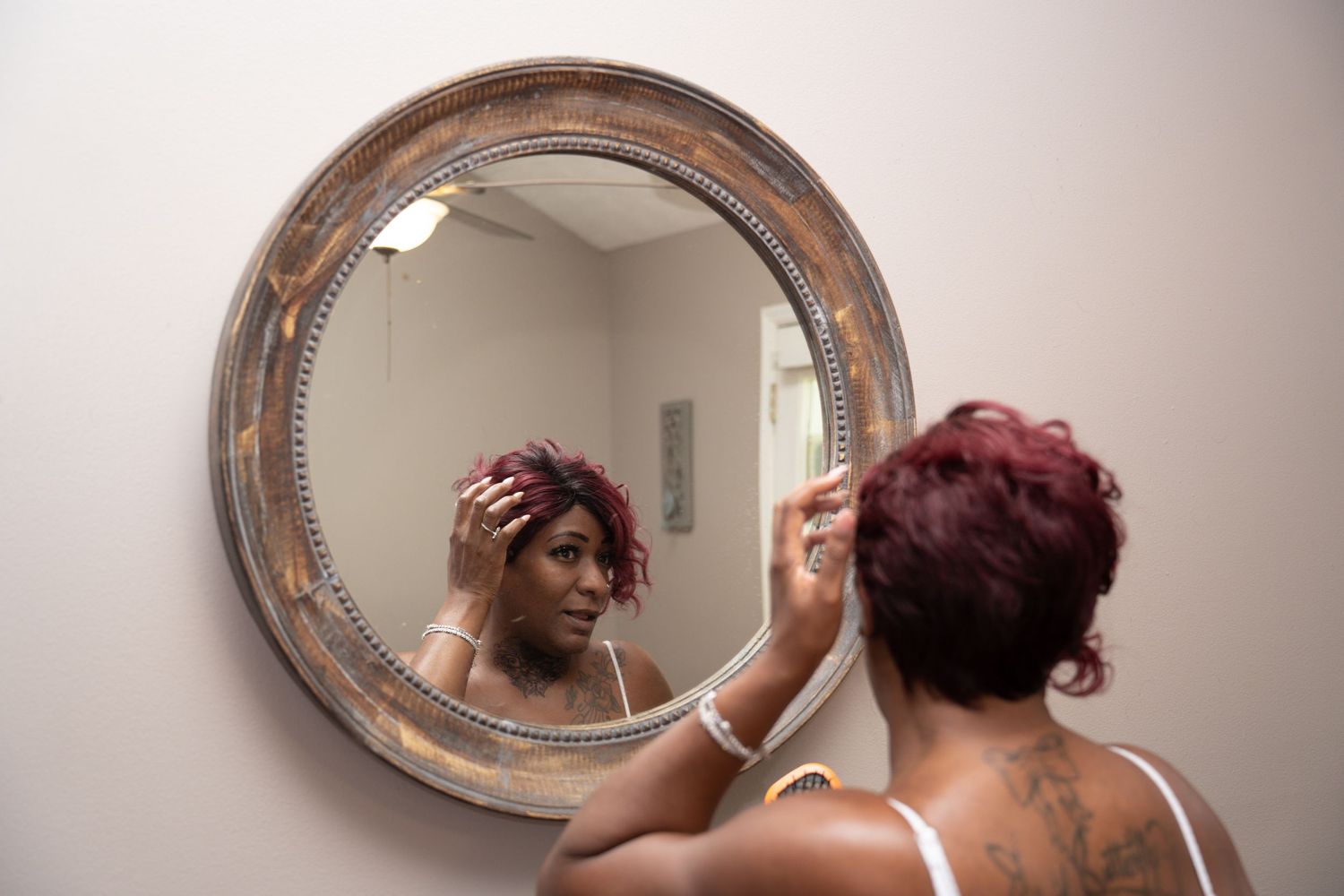 Person getting ready in front of vintage oval mirror during wedding preparations.