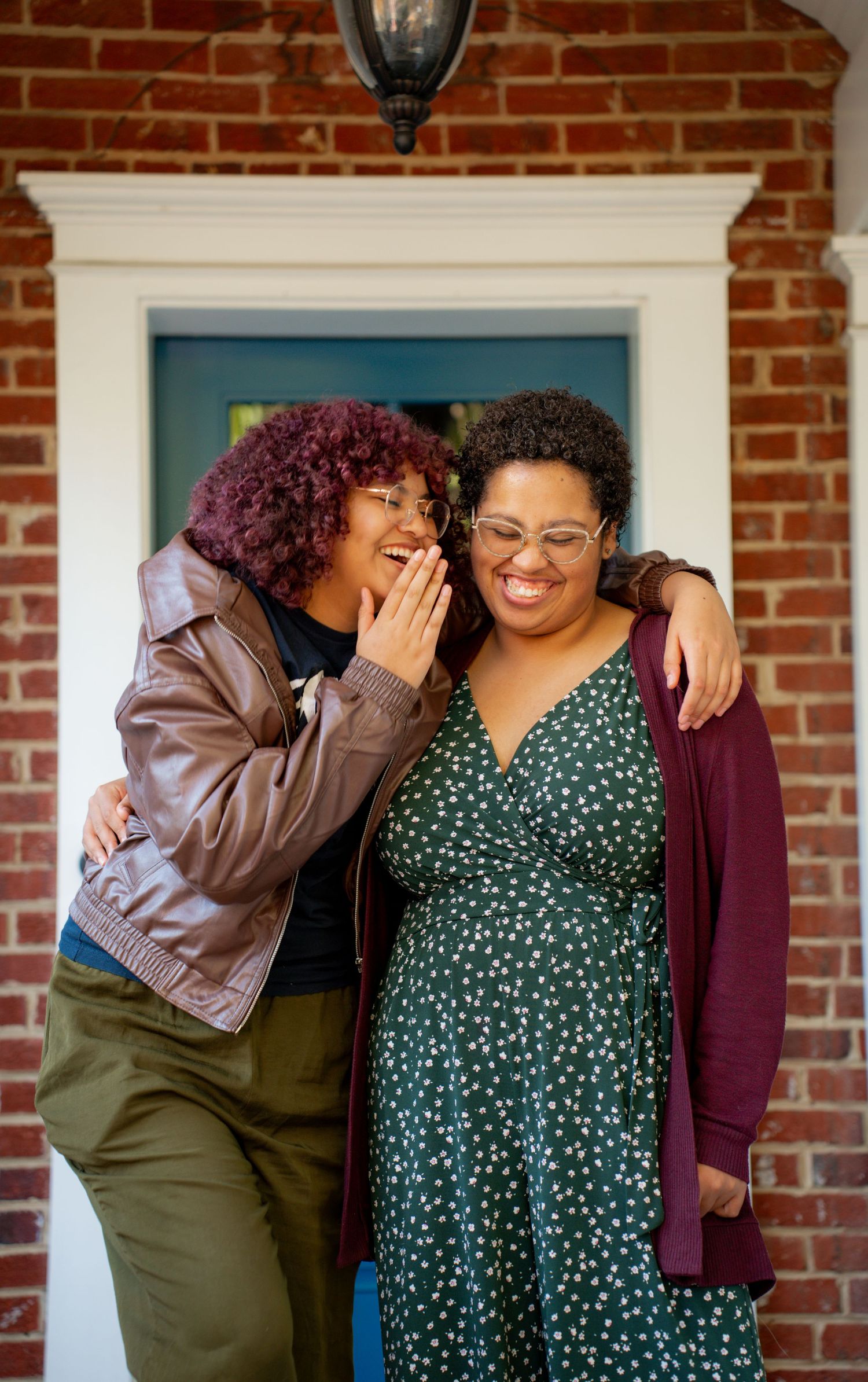 Three candid moments of friends sharing laughter and embraces against a brick wall with white trim windows.