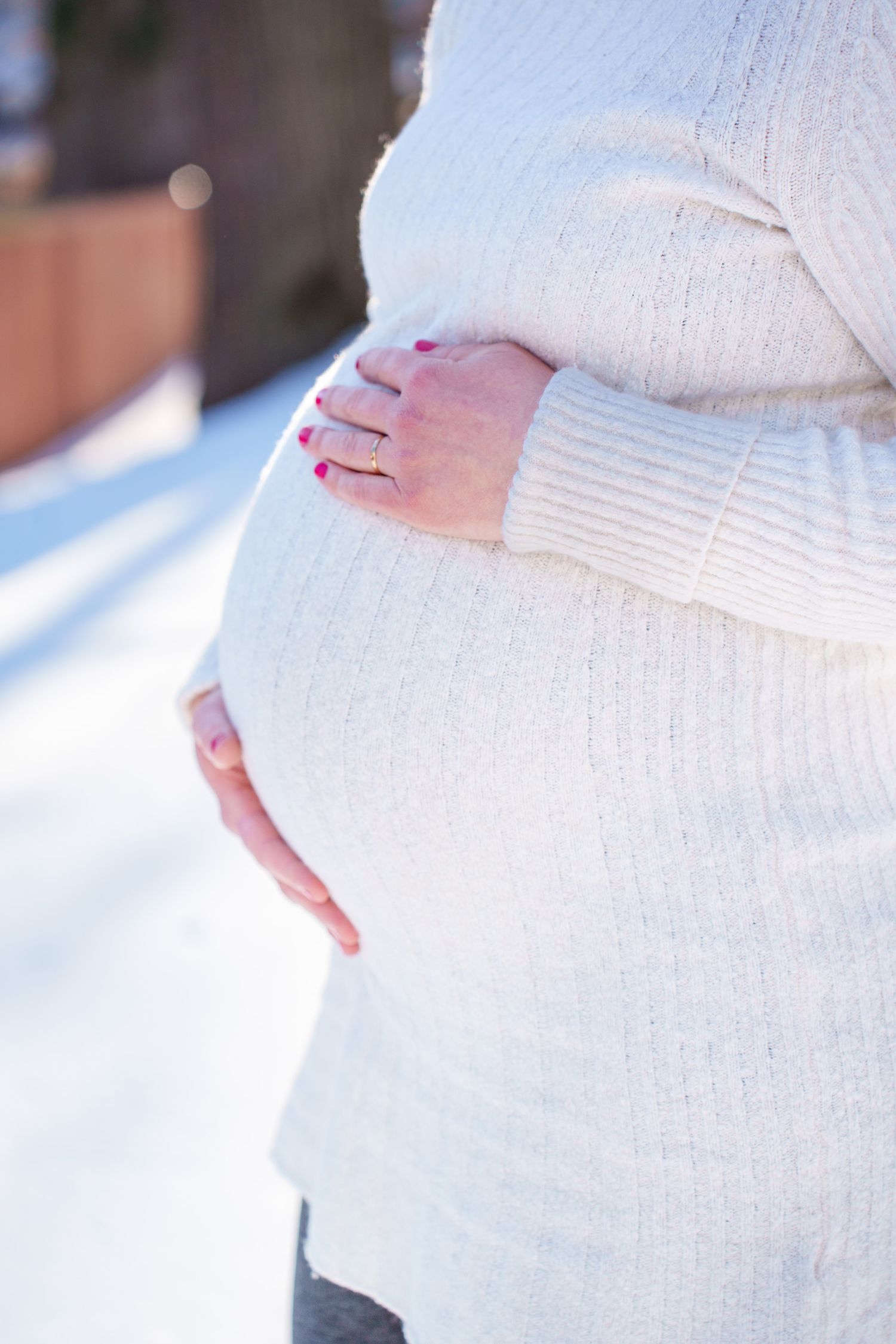 A close-up series of maternity photos showing a pregnant belly in a white dress with hands gently cradling the bump.