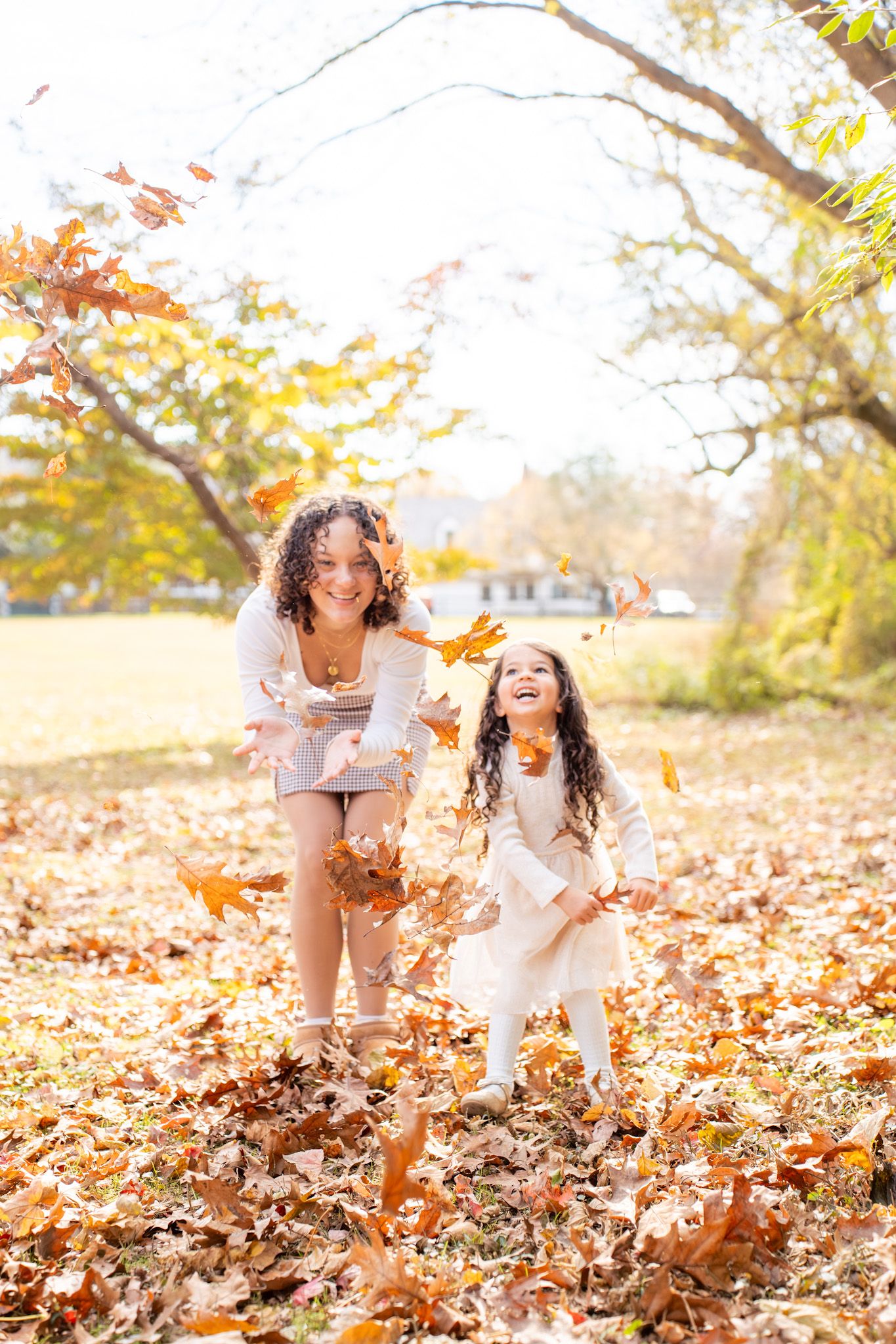 People play together in a field of fallen autumn leaves on a bright sunny day.