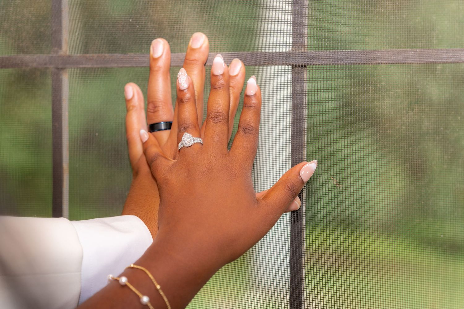 Close-up of hands with wedding rings against window background.