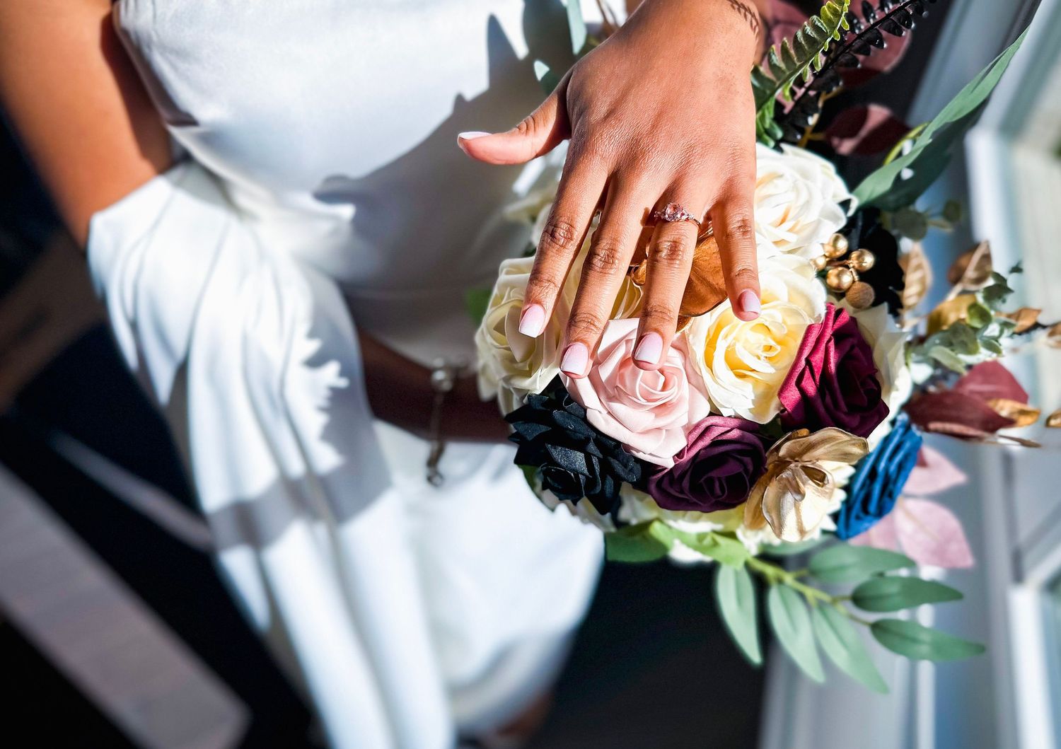 Close-up of hands holding white rose wedding bouquet.
