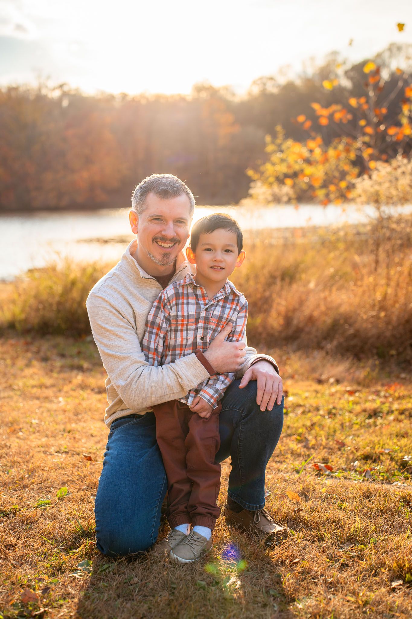 A heartwarming outdoor portrait captured in warm autumn sunlight by a lake.