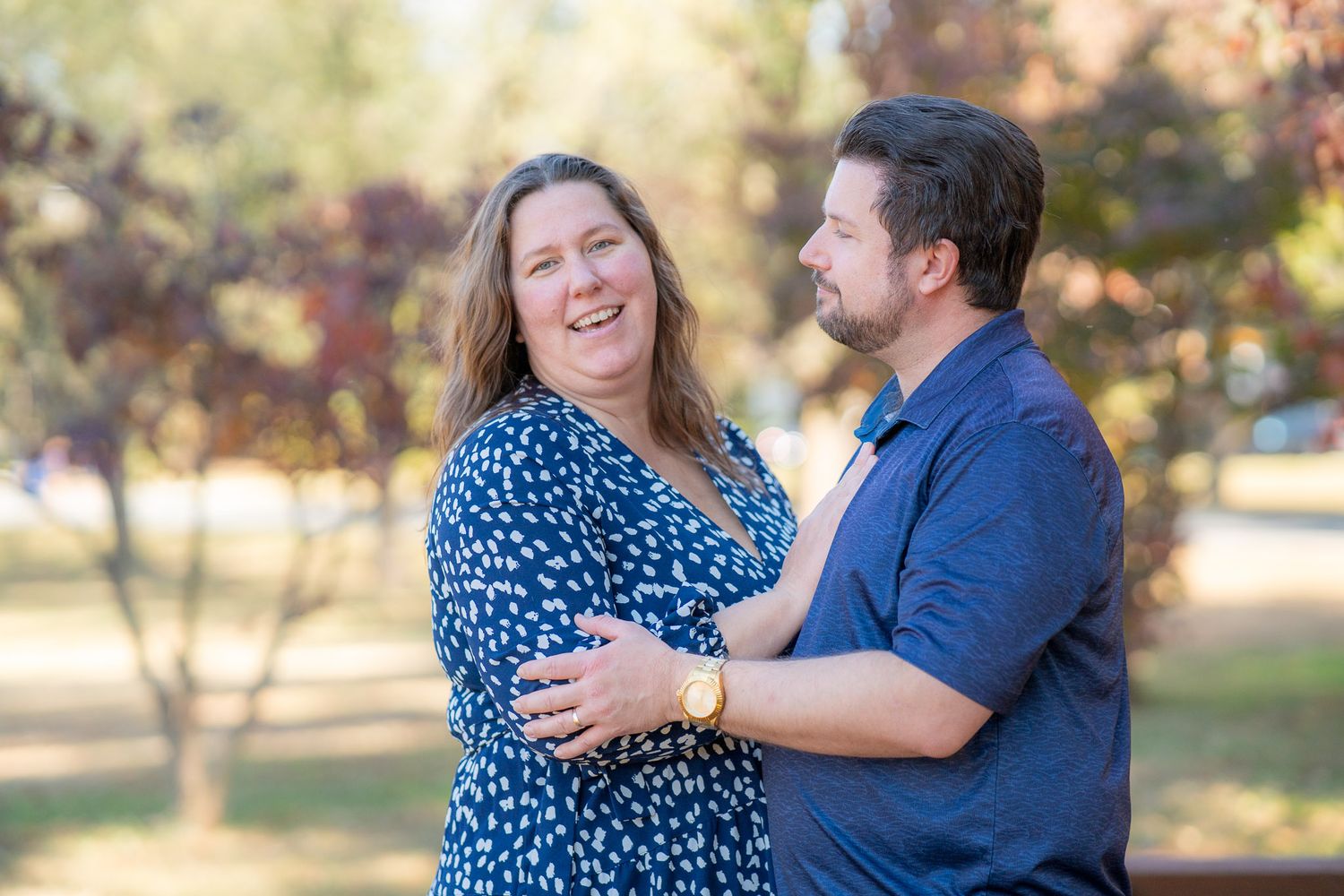 A couple in blue outfits share romantic moments during their outdoor photo session at sunset.