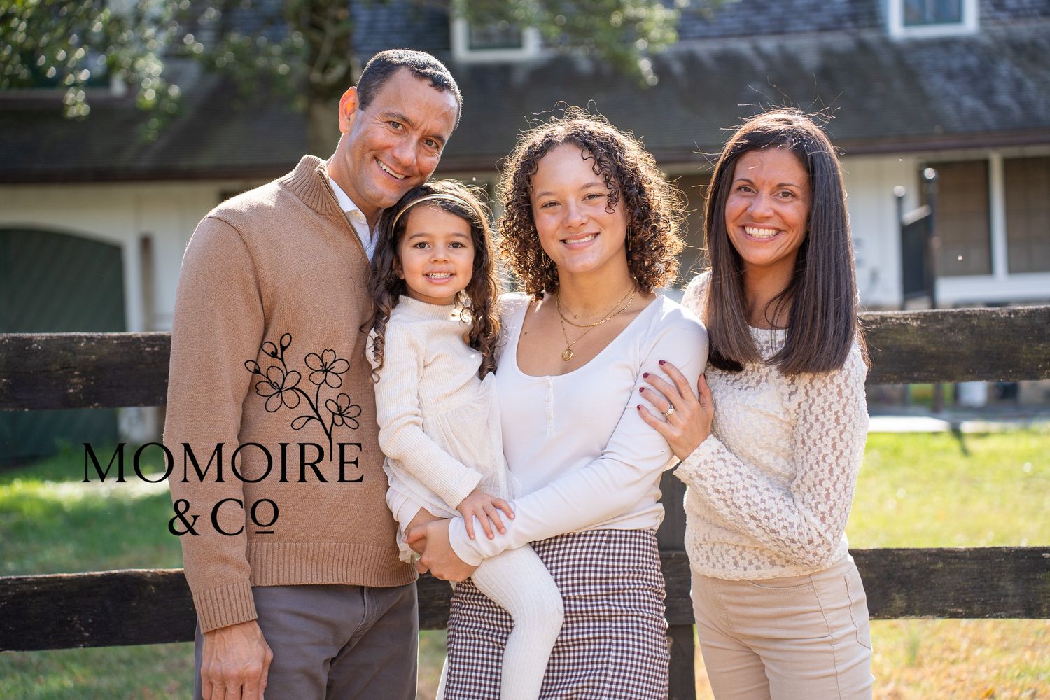 Family group wearing coordinated neutral tones poses together outdoors during autumn photo session.