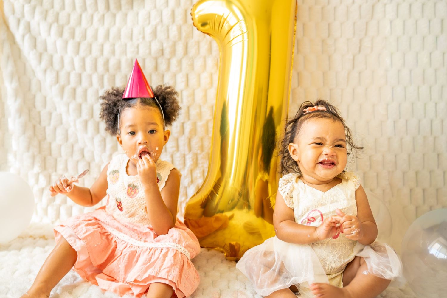 Birthday celebration photo series with baby in white dress against textured wall with gold balloon.