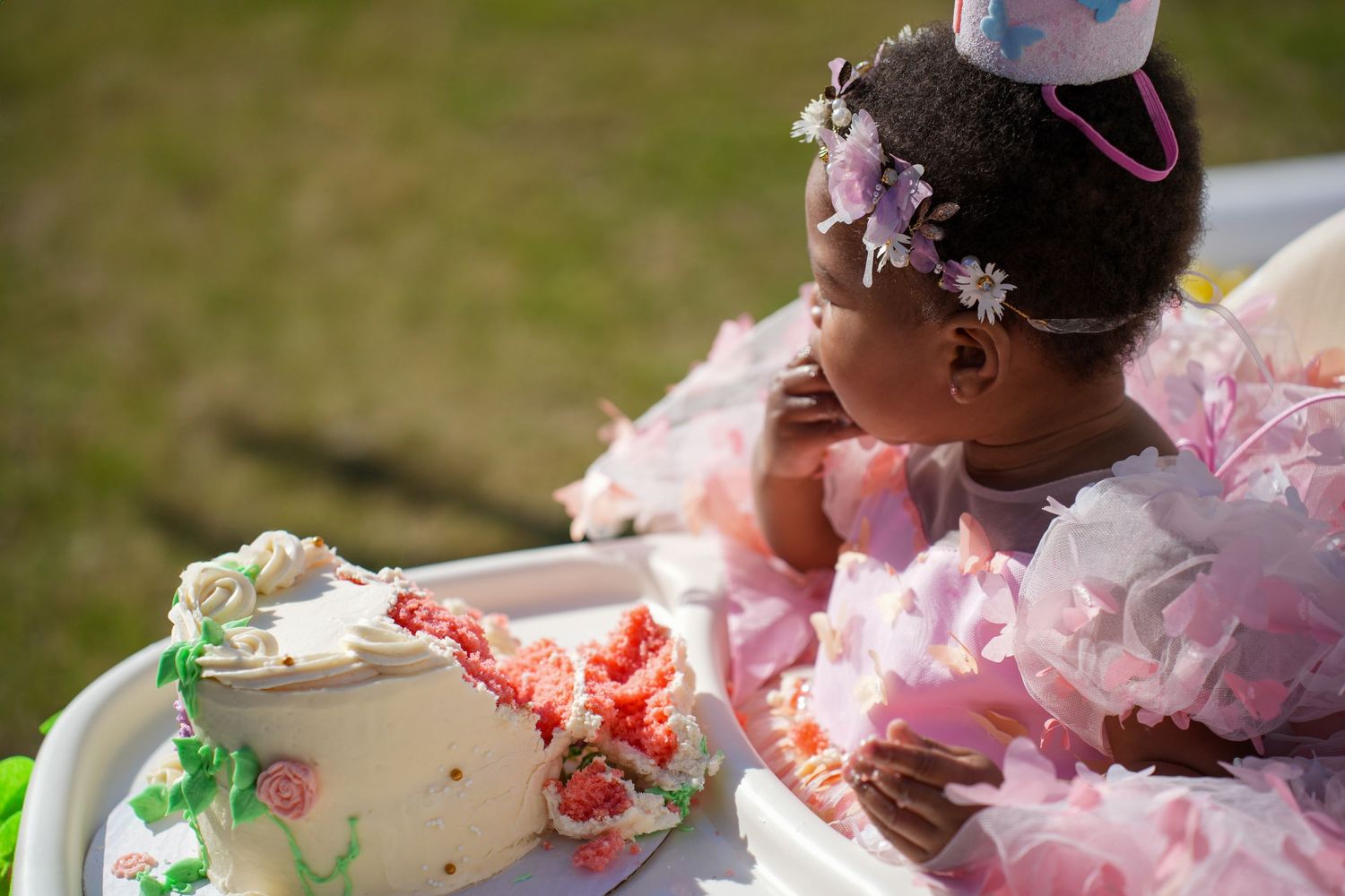 A group of people in formal attire playfully smashing cake into each other's faces at an outdoor celebration.