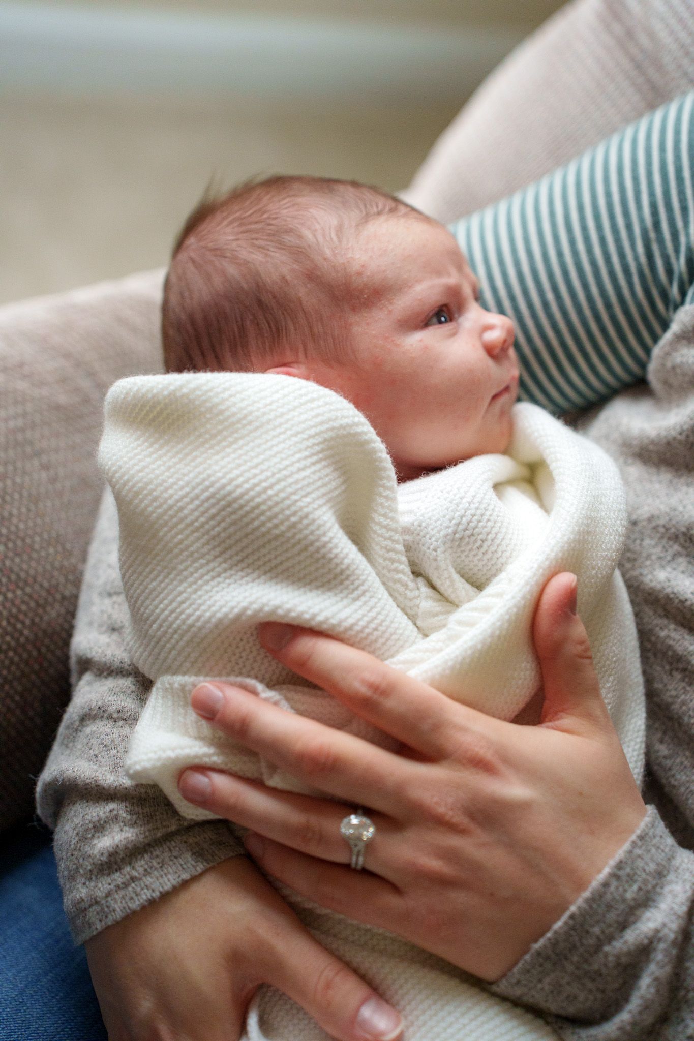 Close-up sequence of hands gently folding and arranging a soft white towel against a neutral background.