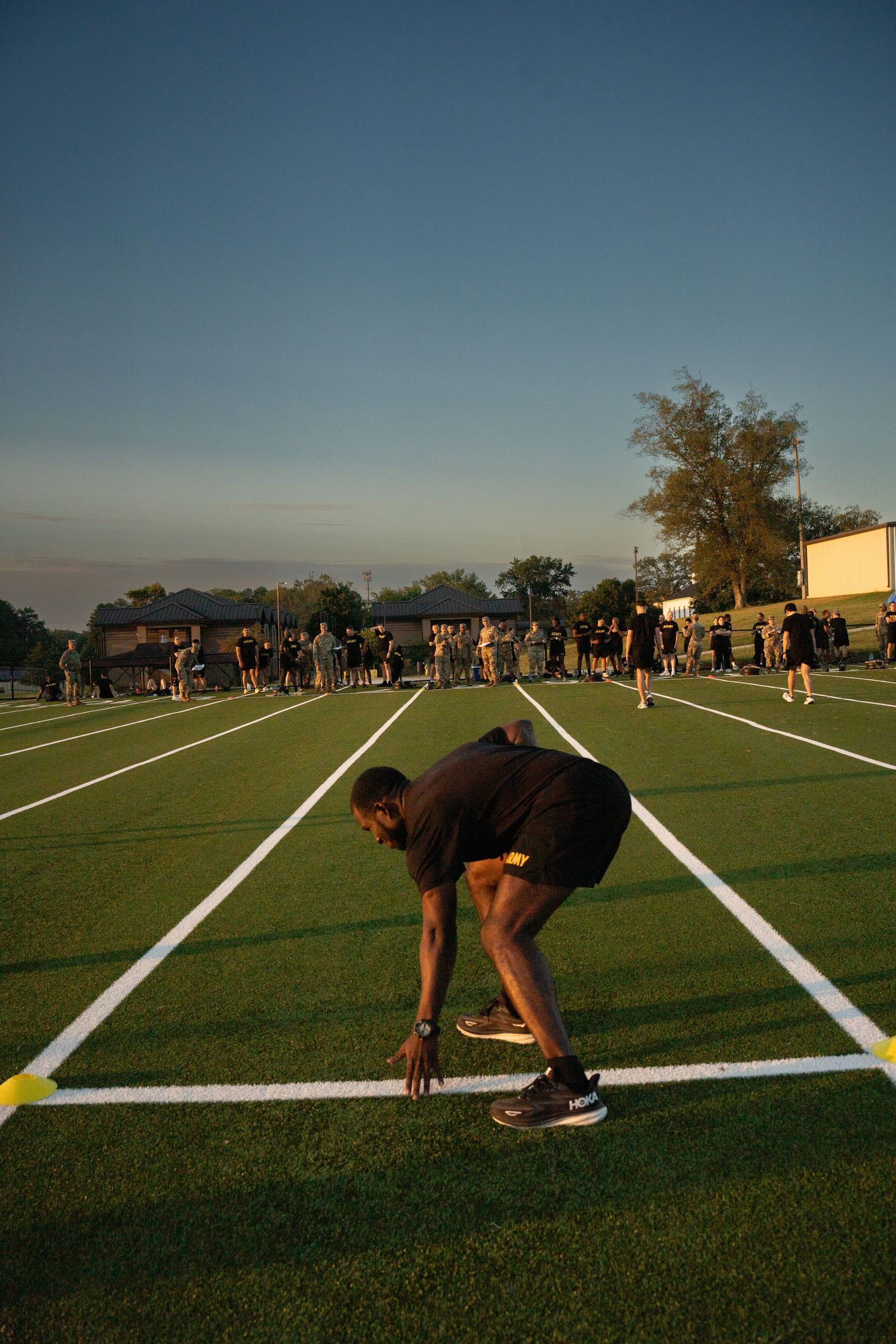 Sequence of four photos showing someone getting into a sprinting position on a sports field at sunset.