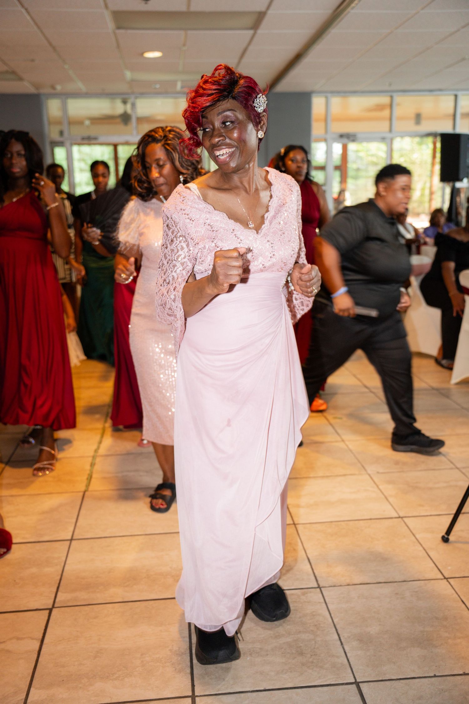 Couple dancing together on a tiled floor at a formal event wearing white and red attire.