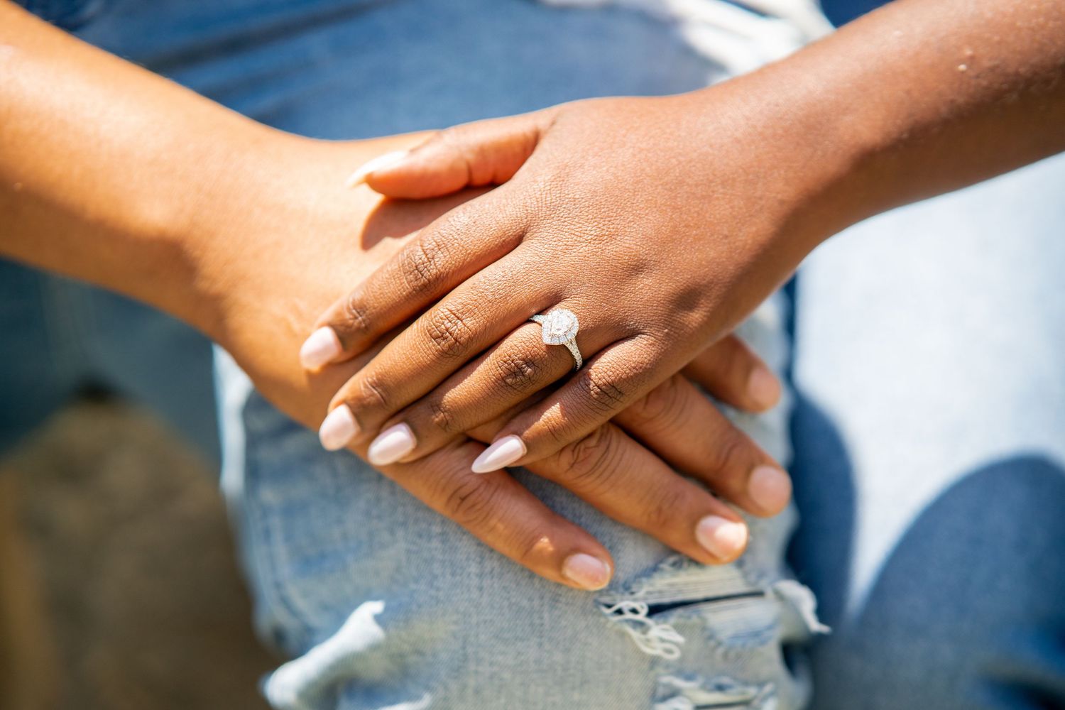 Detail shot of engagement ring and intertwined hands during courthouse photo session.