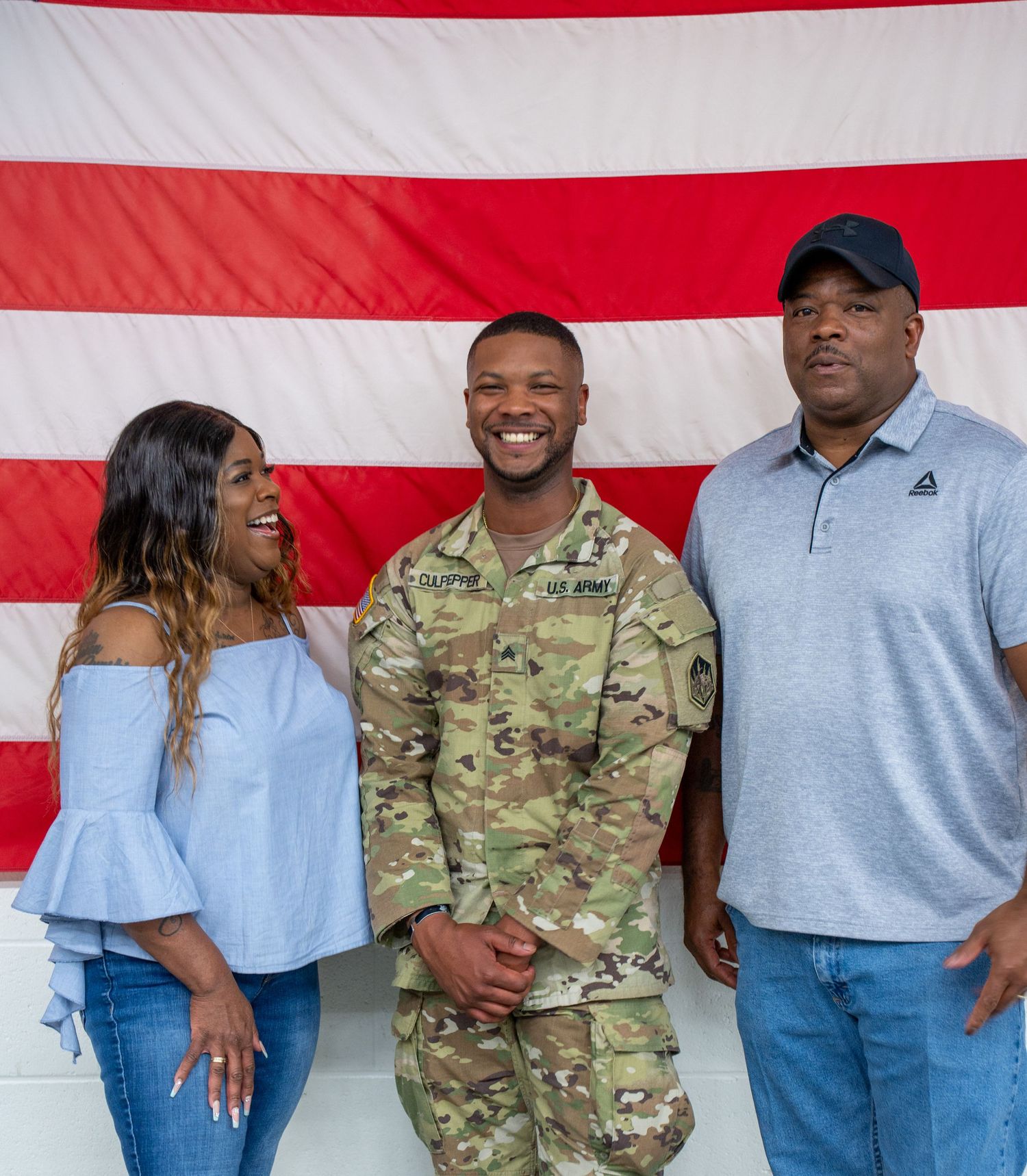 Family members and service members pose together in front of an American flag.