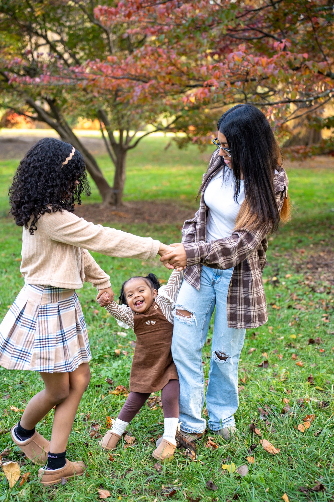Playful movement captured on grass with fall trees and colorful leaves in the background.