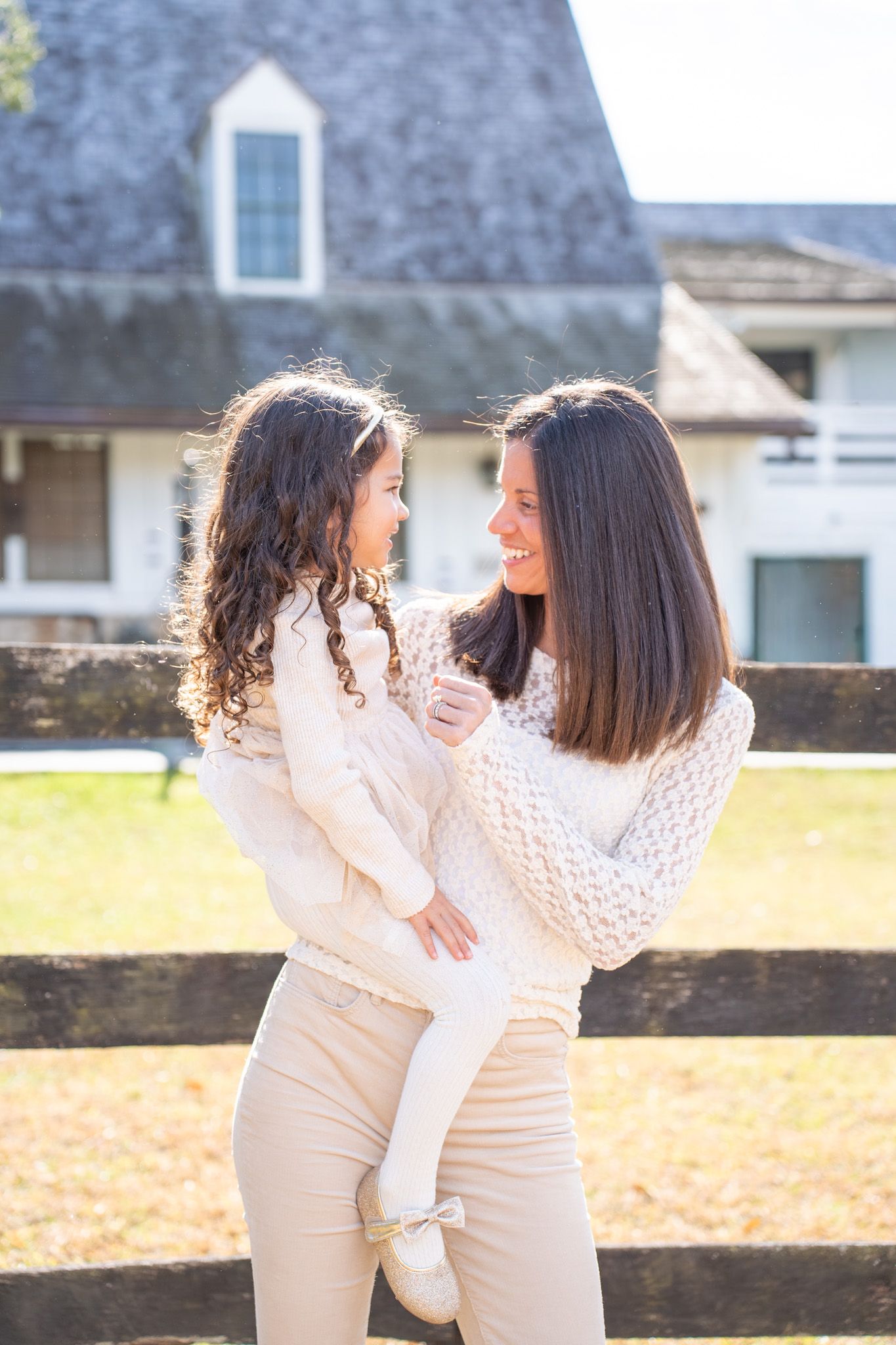 Two people in white outfits share tender moments together in an outdoor setting with a fence and autumn leaves.
