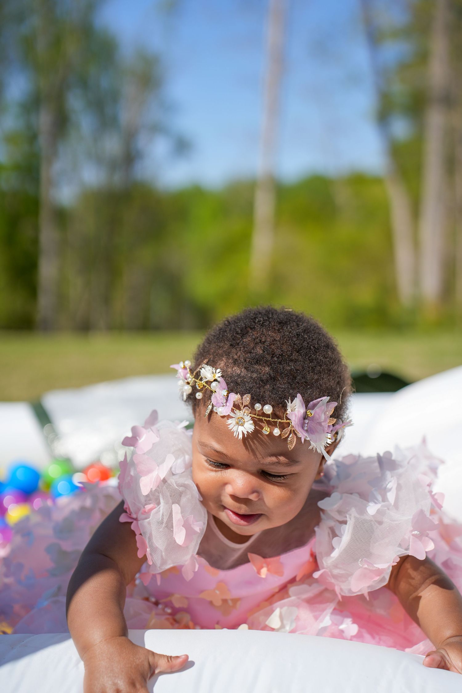 12 month old at first birthday party in pink dress on a sunny day.