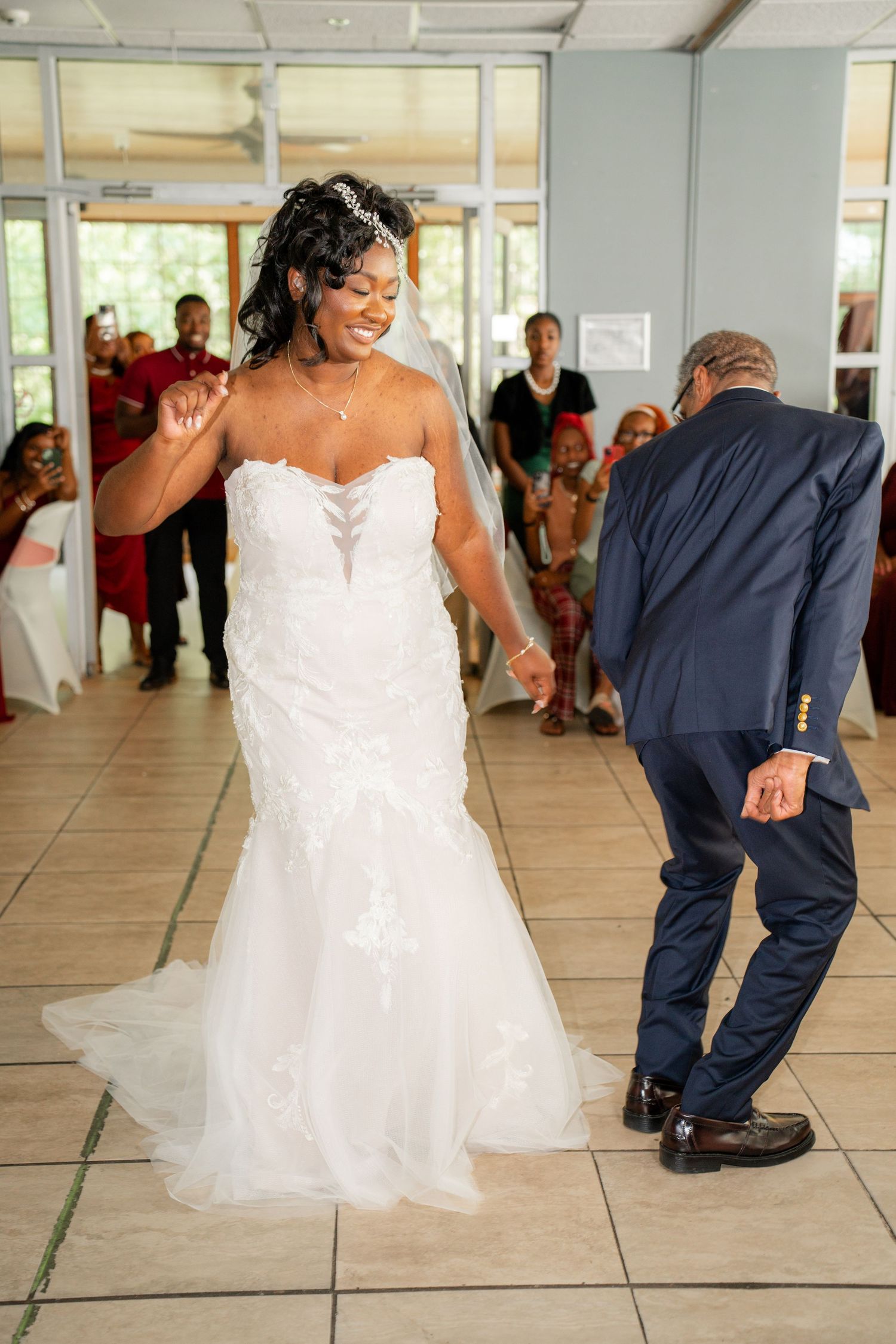 Wedding couple performs fun dance moves on the reception floor in coordinating white dress and navy suit.