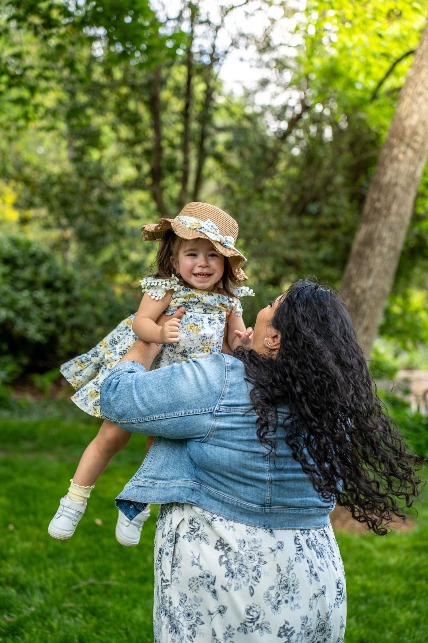 Playful spinning sequence in a sunny garden wearing a floral dress and denim jacket.