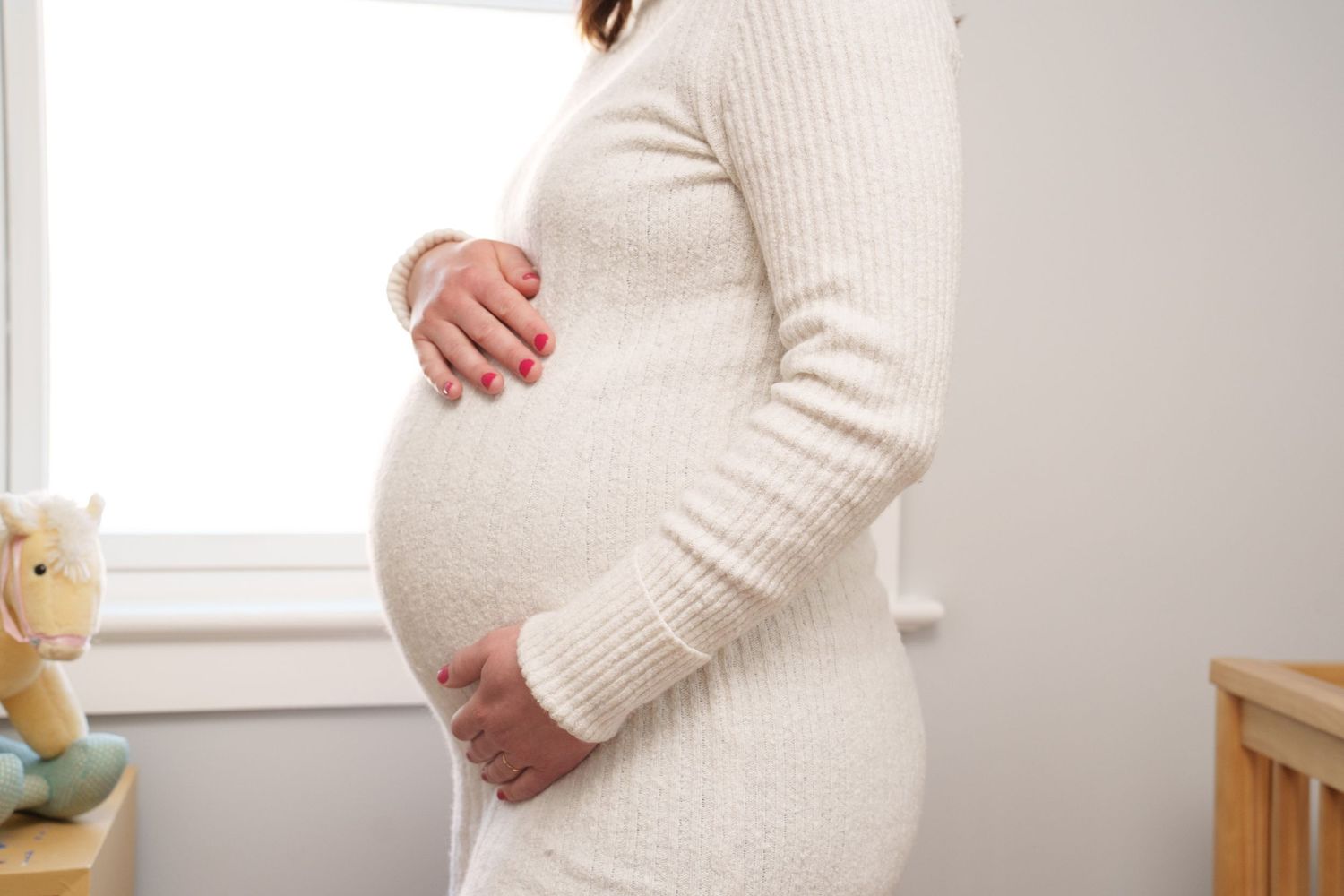Side view of a pregnant woman in a cream sweater showing the progression of her growing belly through multiple photos.