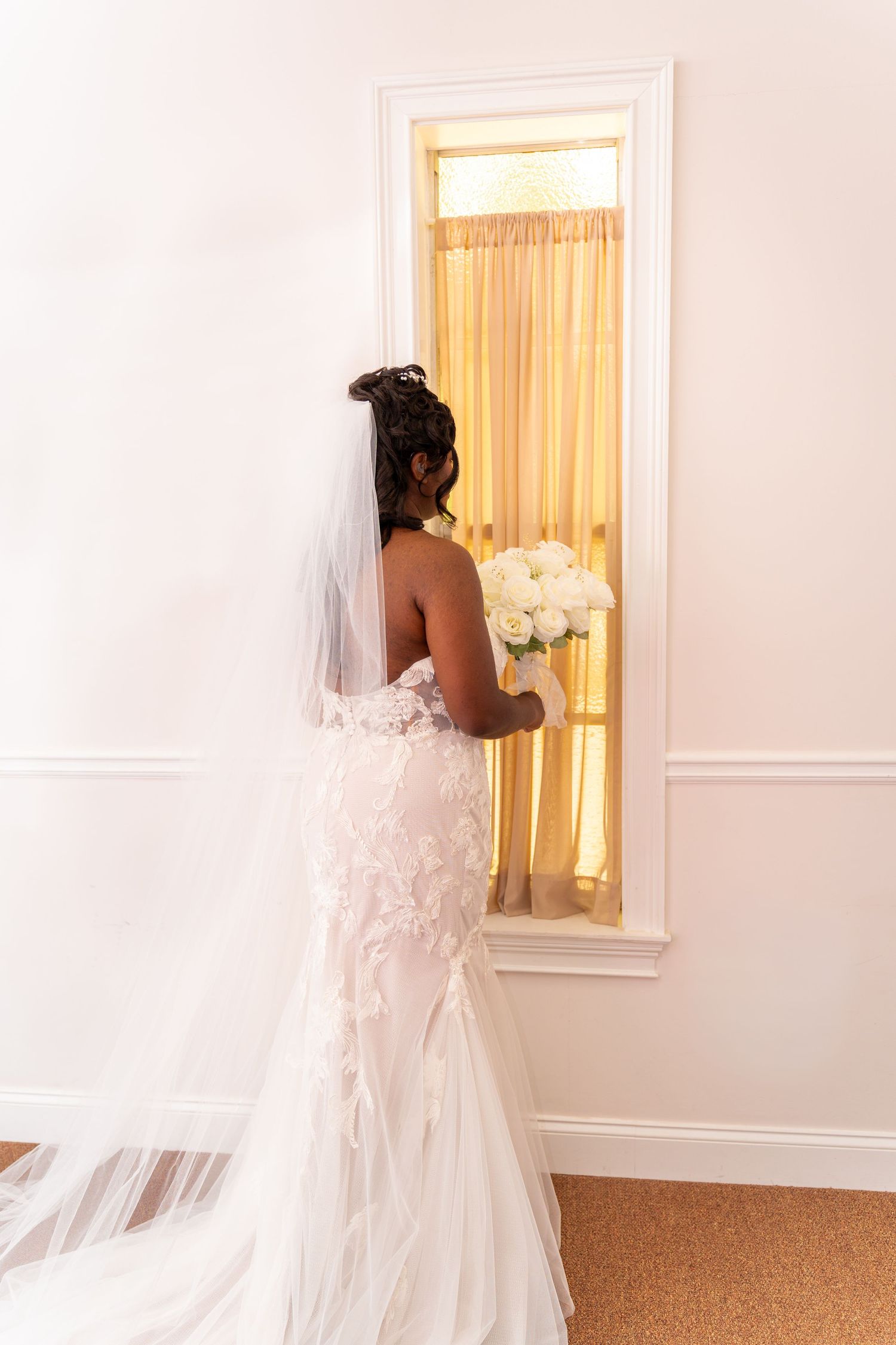 Back view of wedding dress with delicate lace details and flowing veil.