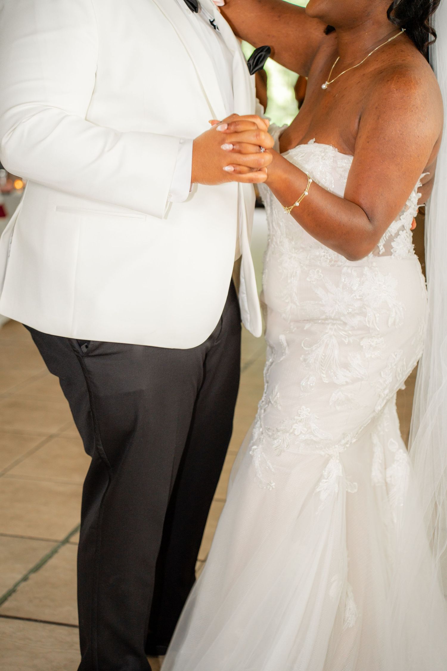 Wedding couple in white formal attire dancing together at their reception.
