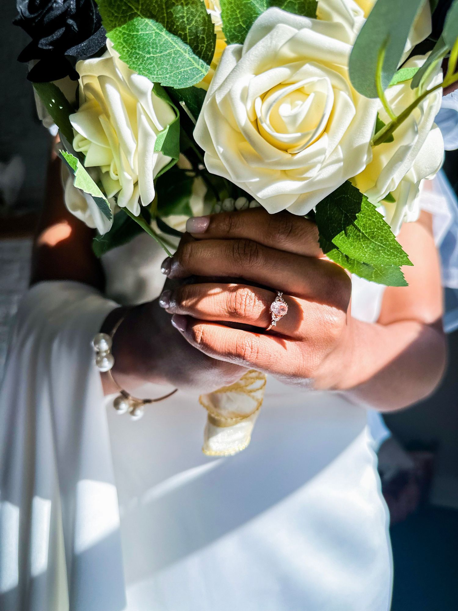 White roses in a bridal bouquet with delicate green foliage.