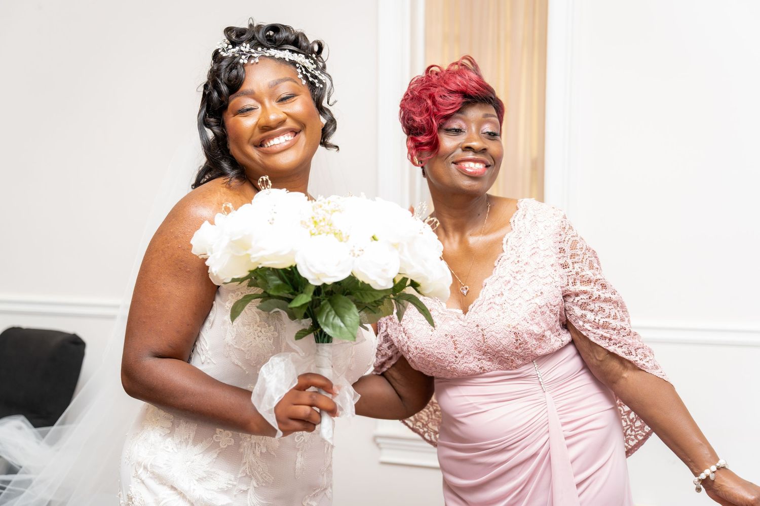Wedding party members in pink dresses sharing laughs and embraces.