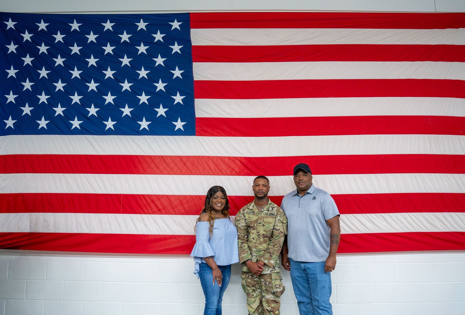 Service members and families gather for a military ceremony with American flag backdrop.