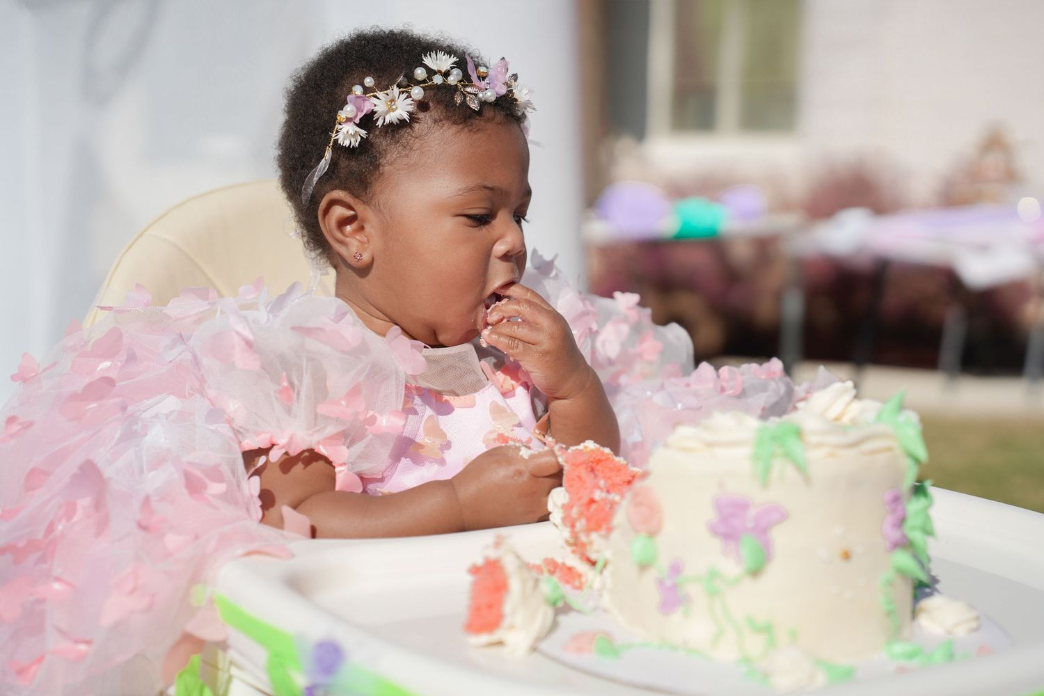 Birthday celebration scene with cake, pink decorations and floral accessories.