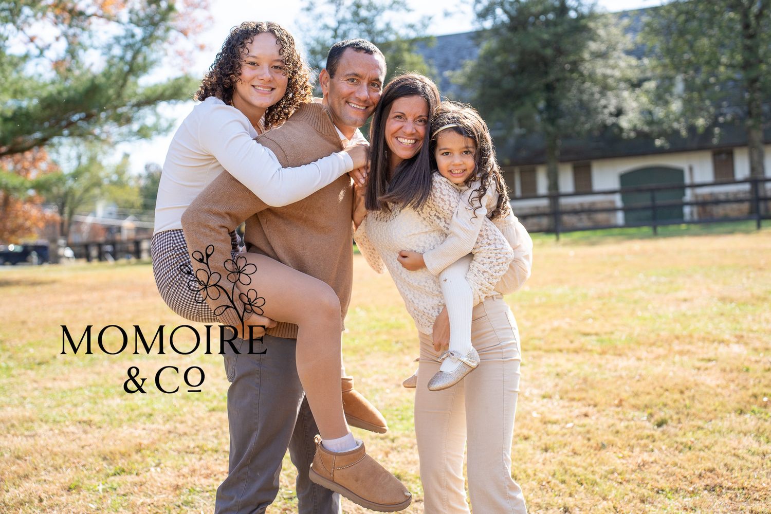 A loving family embraces and laughs together during an outdoor autumn photoshoot in a golden field.