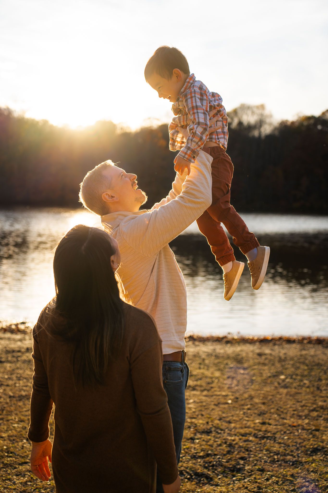 Family enjoying a tender moment together during golden hour at a lakeside beach.
