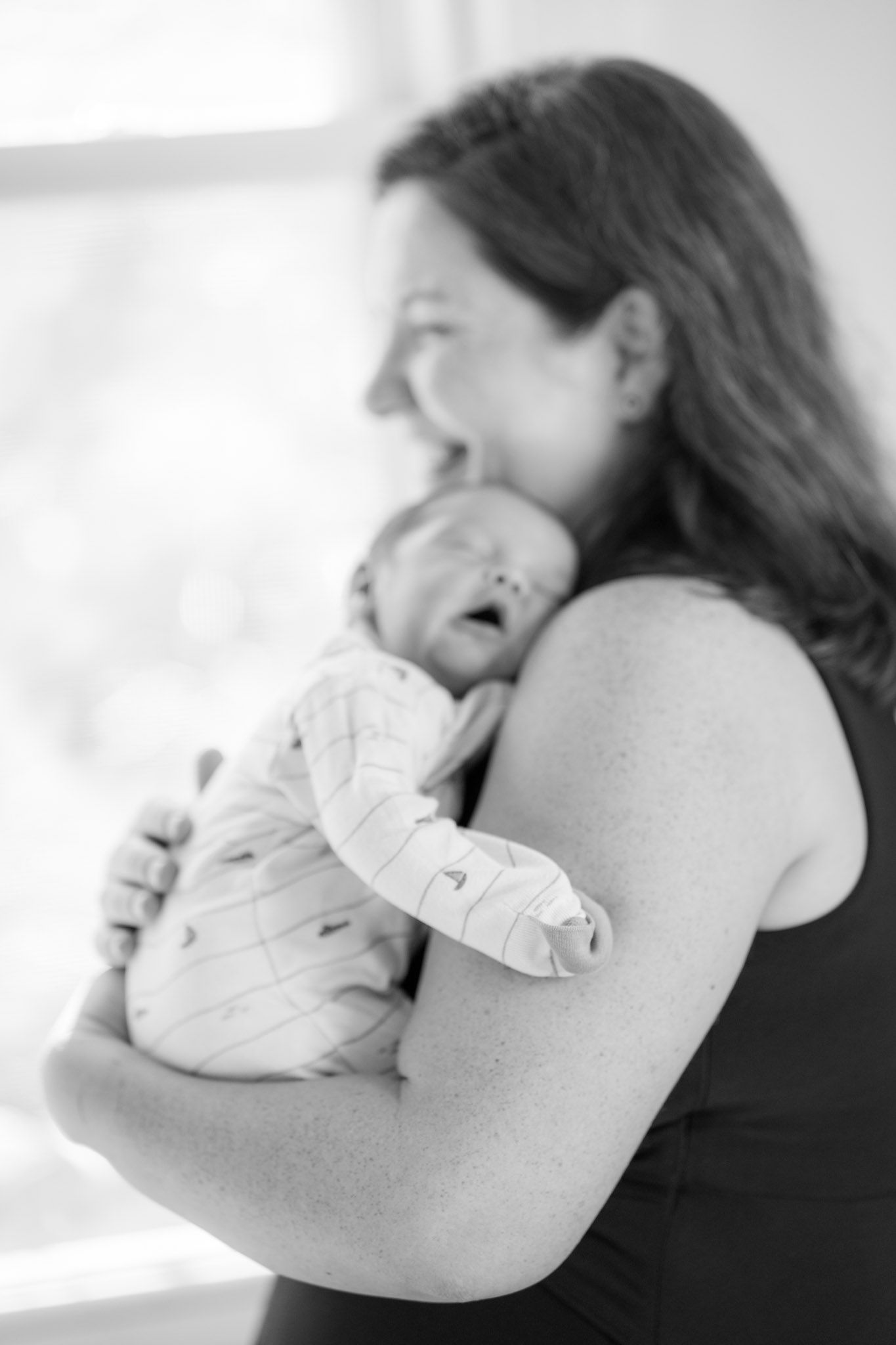 A tender black and white photo series showing a mother cradling and bonding with her newborn baby.