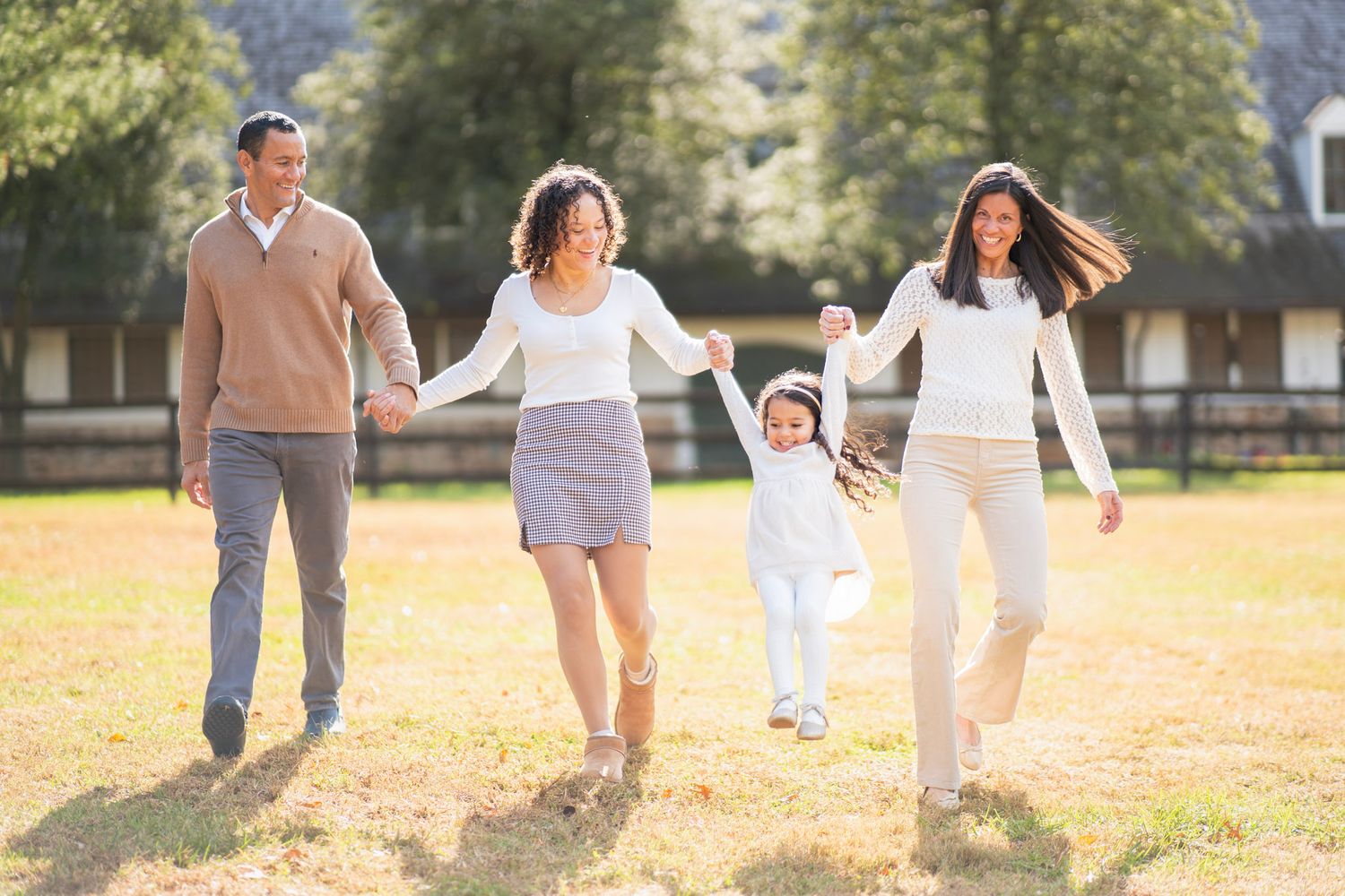 Family members walking together and holding hands in a sunny park during autumn season.