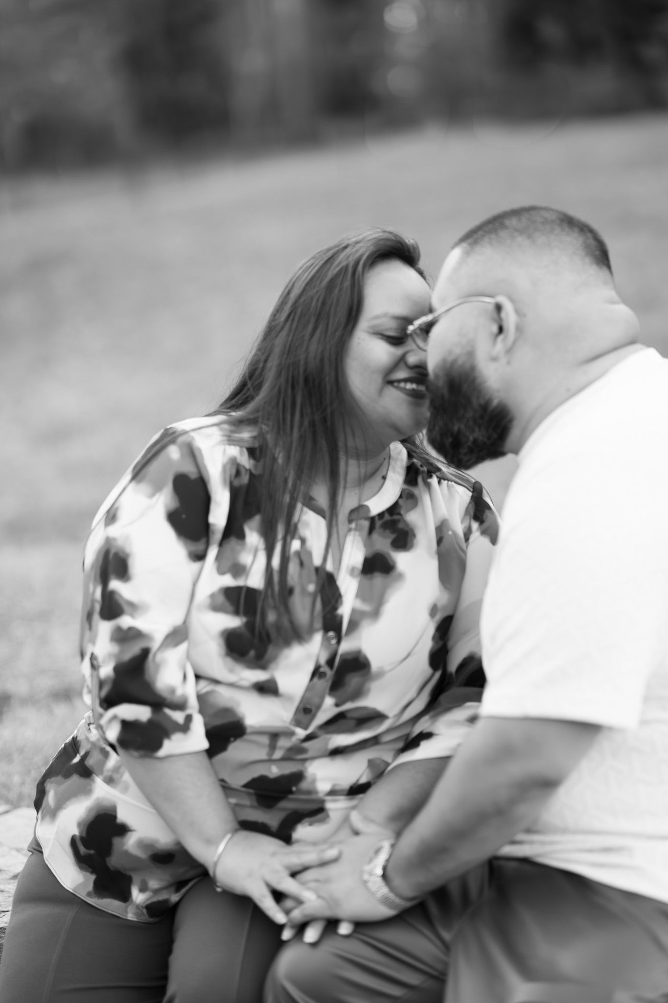 A romantic couple shares tender moments in a black and white photo sequence while sitting outdoors.