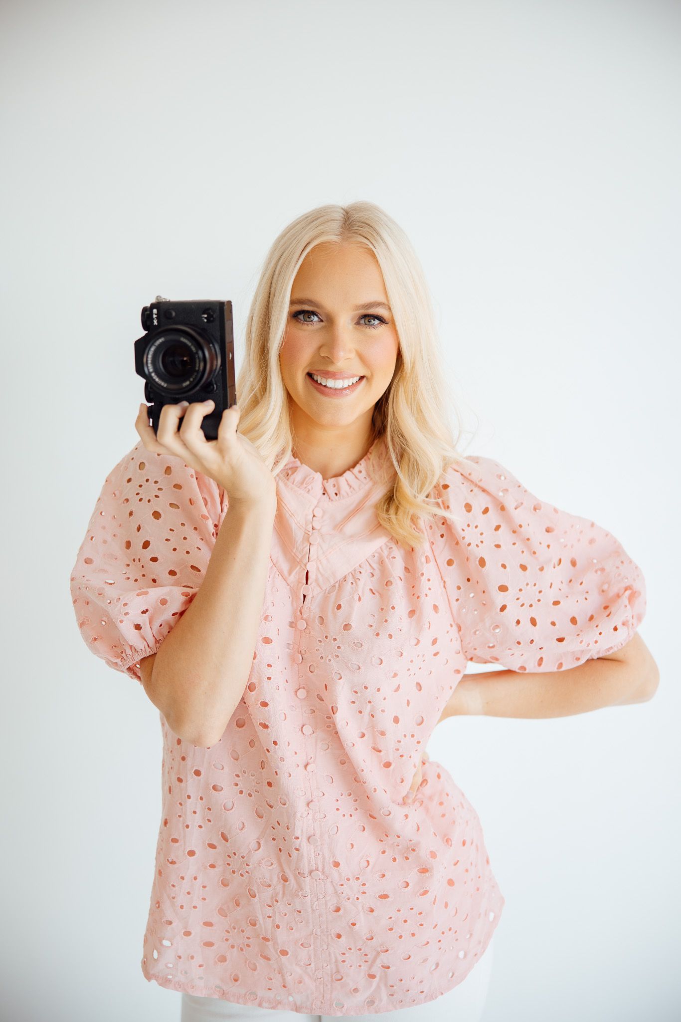 Portrait session against white background with a vintage camera as prop.