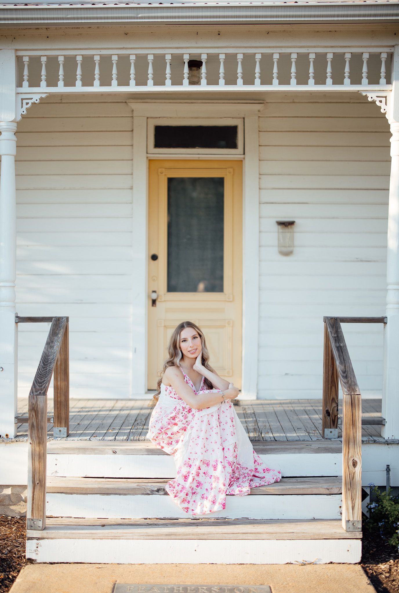 A white farmhouse porch with decorative trim and wooden steps features three matching yellow doors in a row.