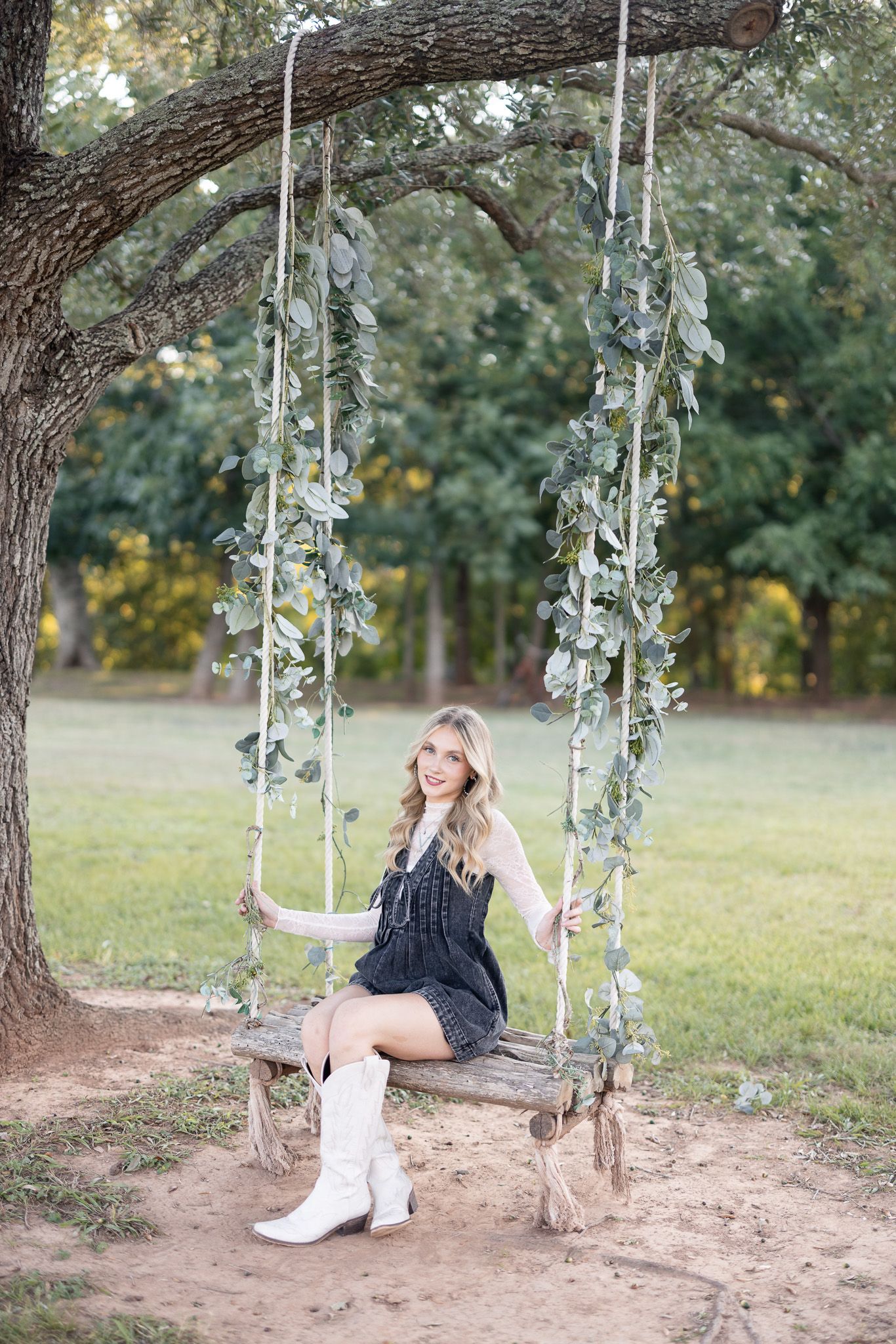 A series of photos showing someone in a dark dress sitting on a rustic tree swing decorated with fairy lights.