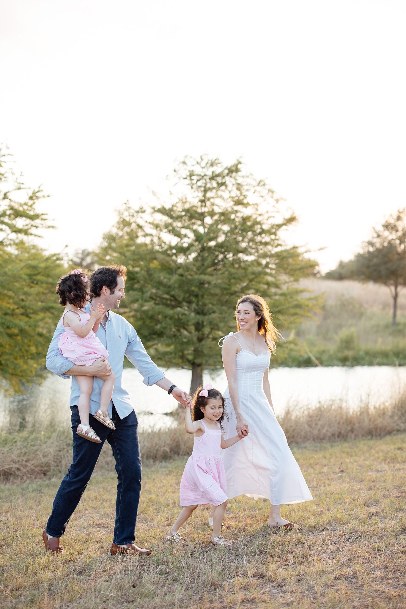 A sequence of four photos showing a dancing family having fun together in a grassy field at sunset.