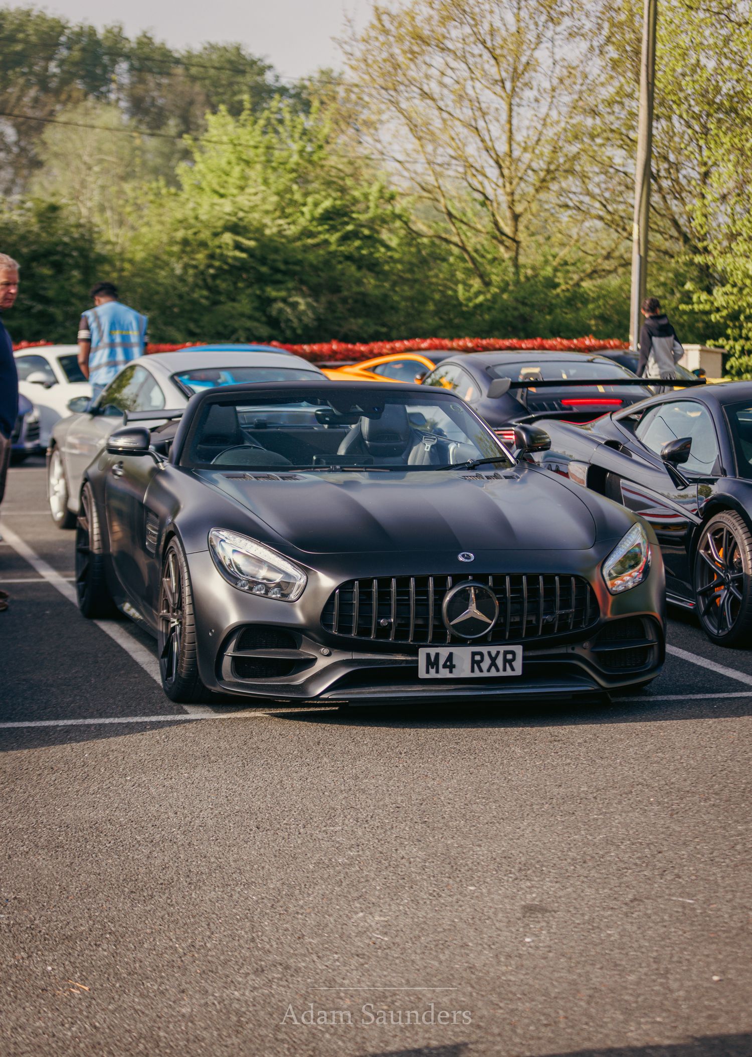 A sleek gray Mercedes-AMG GT sports car parked in a lot showcases its aggressive front-end design and iconic grille.