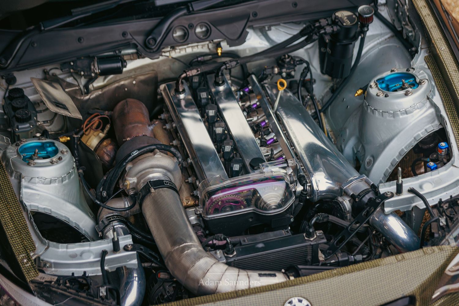 High-performance turbocharged engine bay with polished intake manifold, turbo setup, and custom modifications on a sports car.