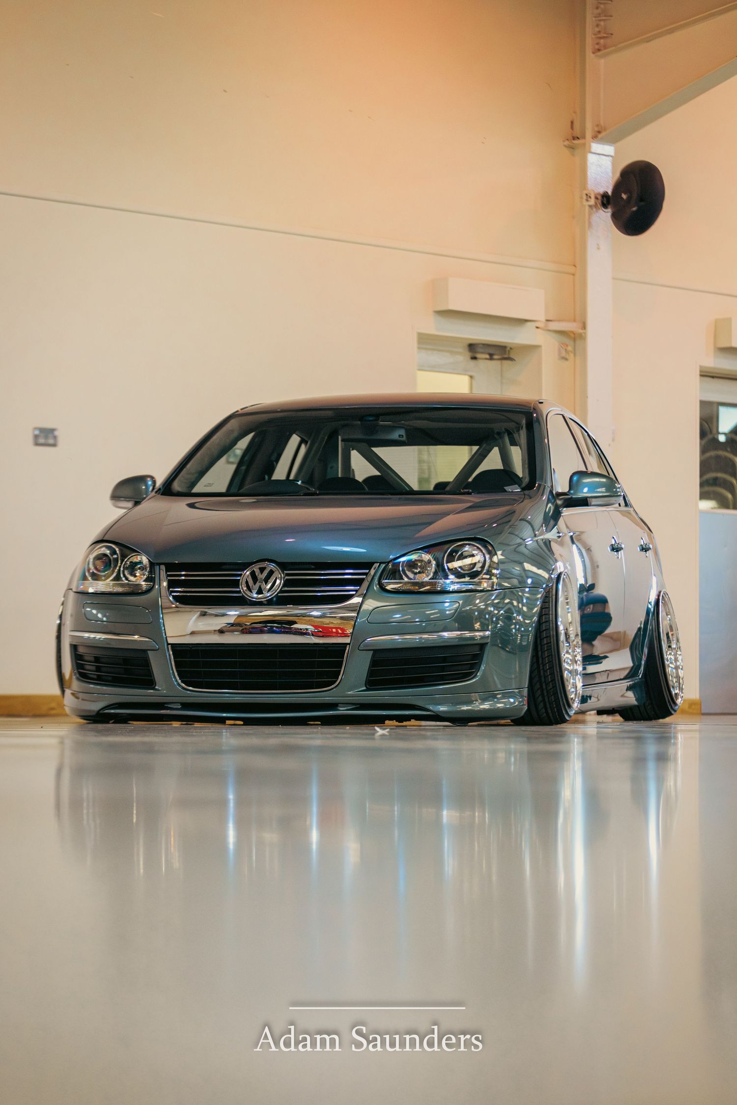 Modified silver Volkswagen Jetta with lowered suspension and aggressive styling sits in a clean indoor parking garage.