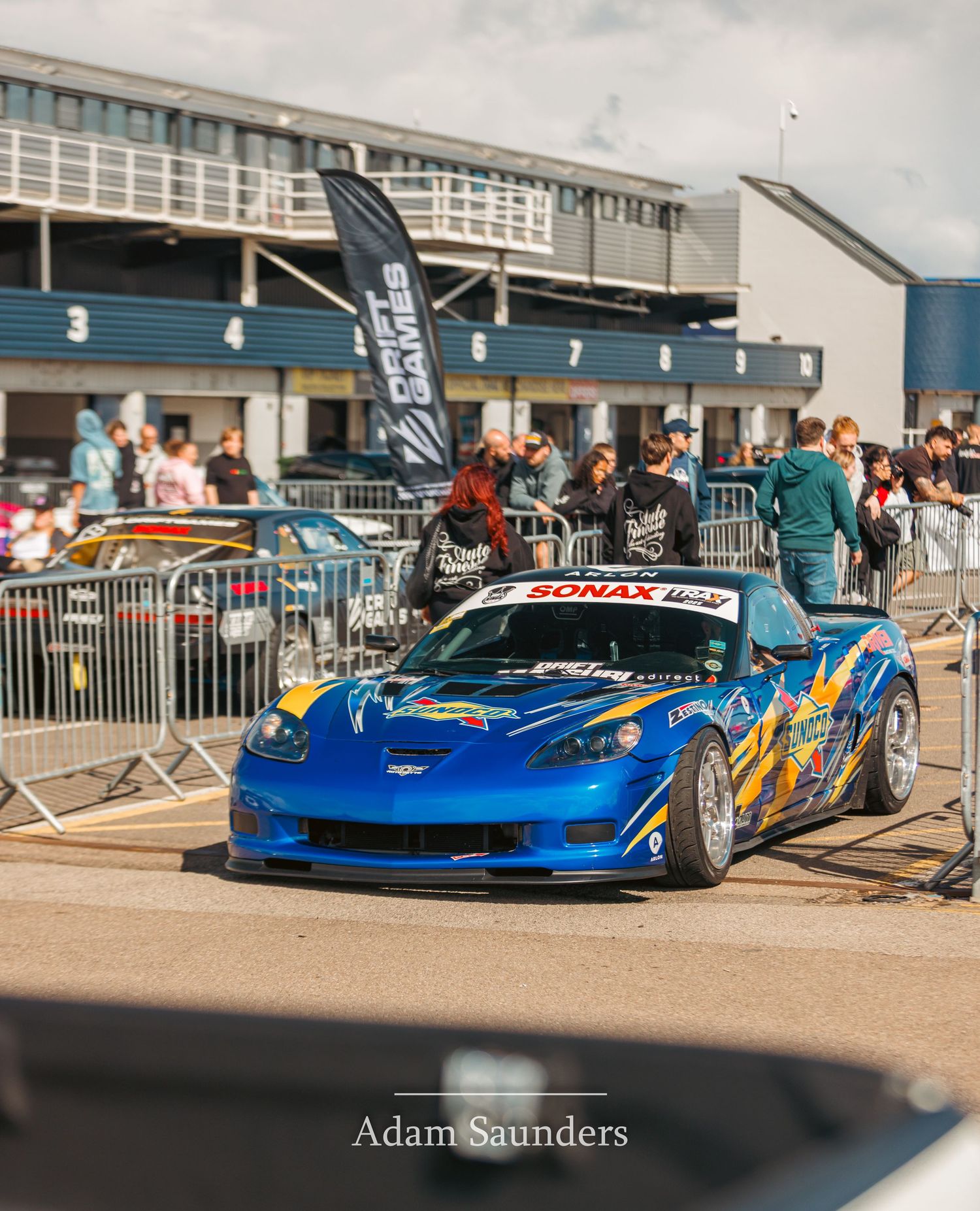 Modified blue sports car with custom body kit displayed at outdoor car show event.