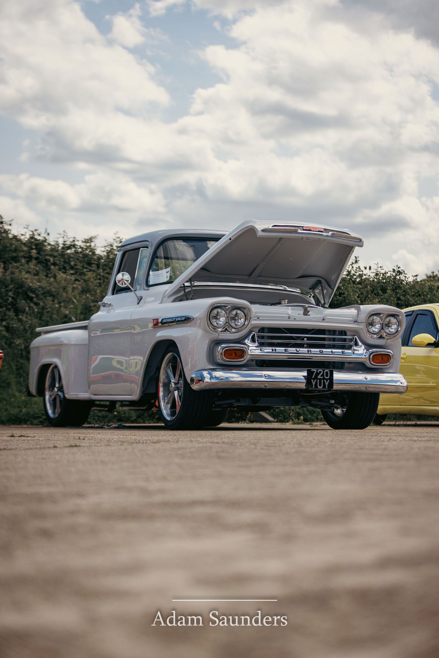 A classic white Chevrolet Apache pickup truck with chrome trim parked outdoors under a cloudy sky.