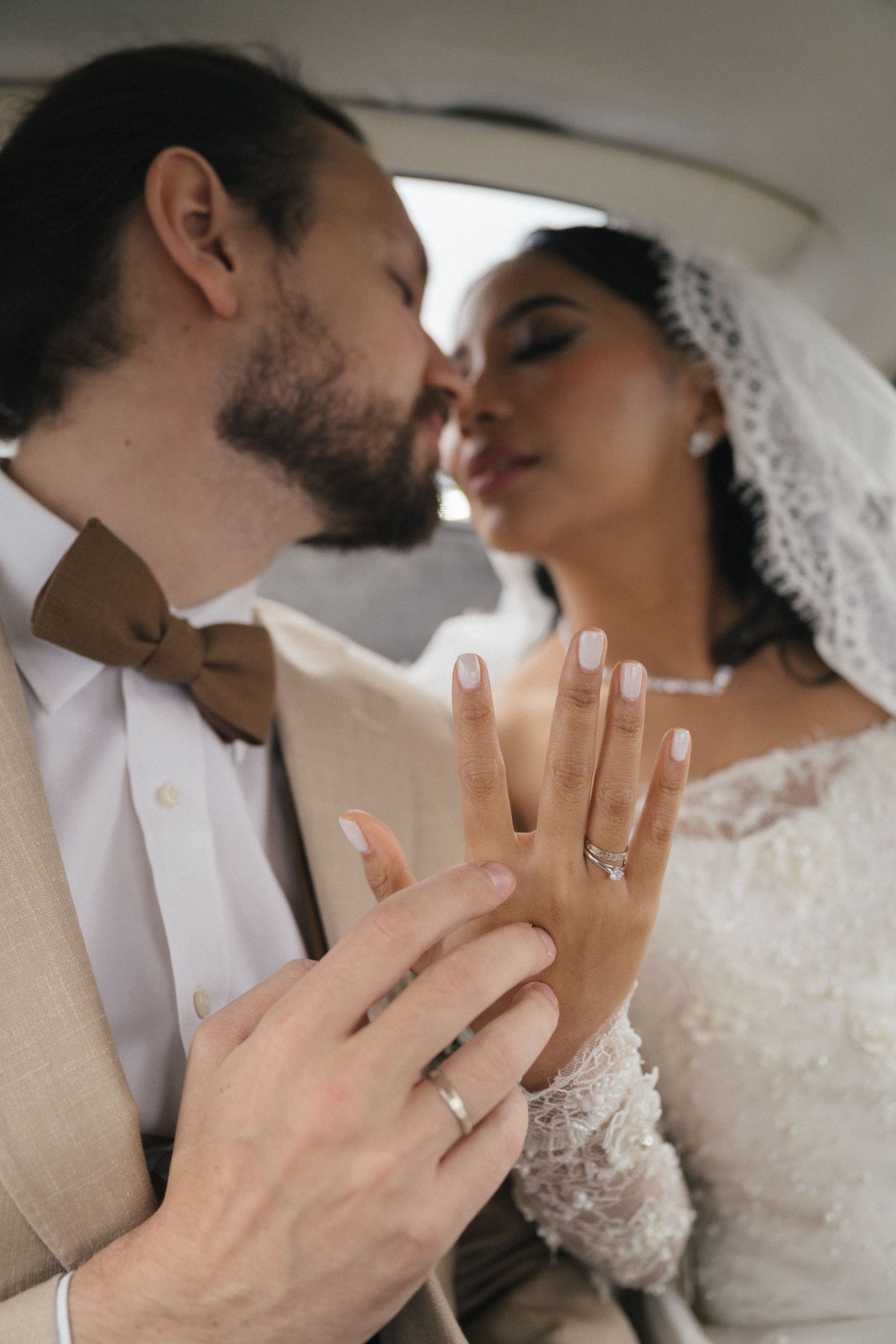 Couple kissing in a vintage car while showing off their wedding ring