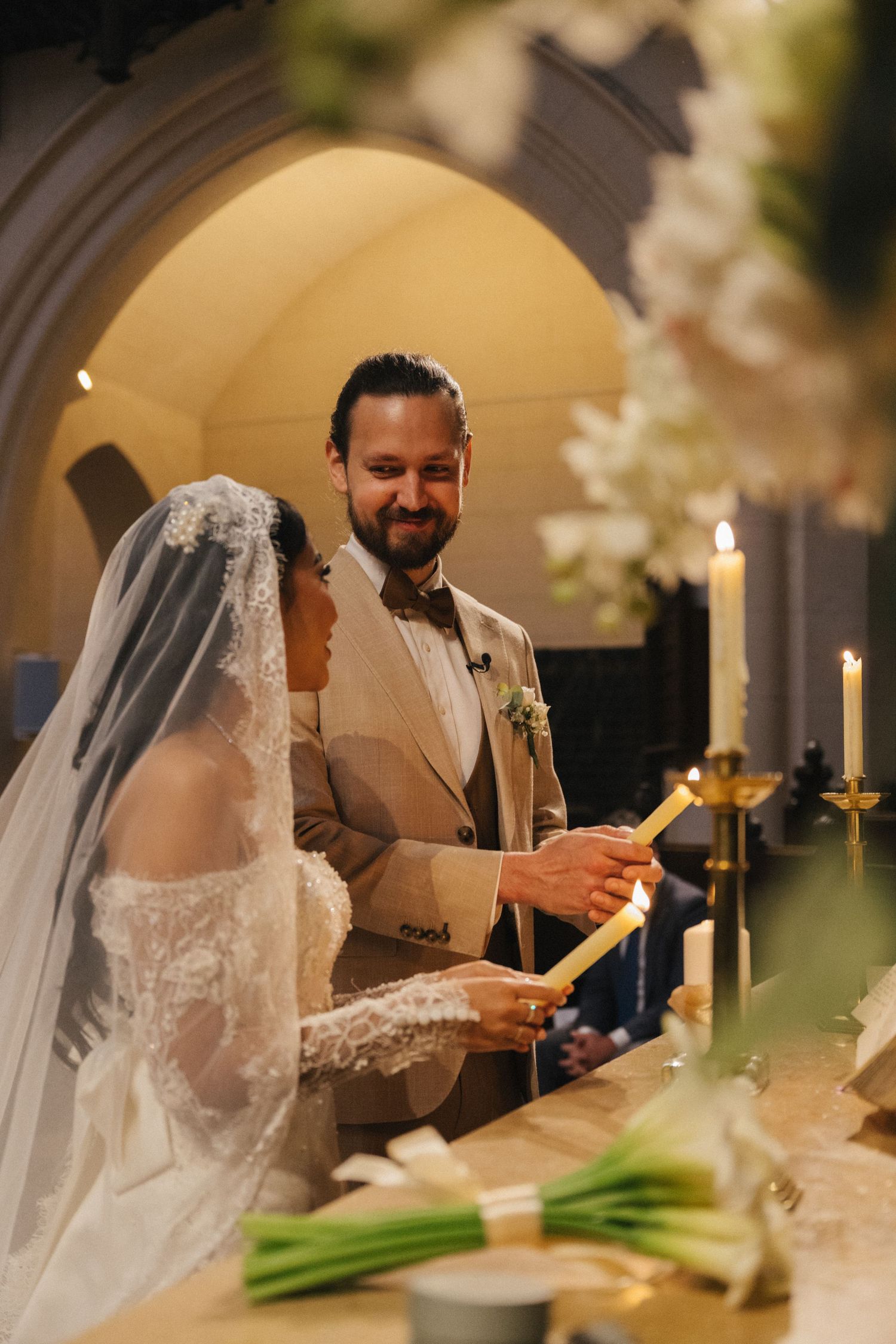 American Church in Paris wedding ceremony, bride and groom looking at each other while lighting up a candle